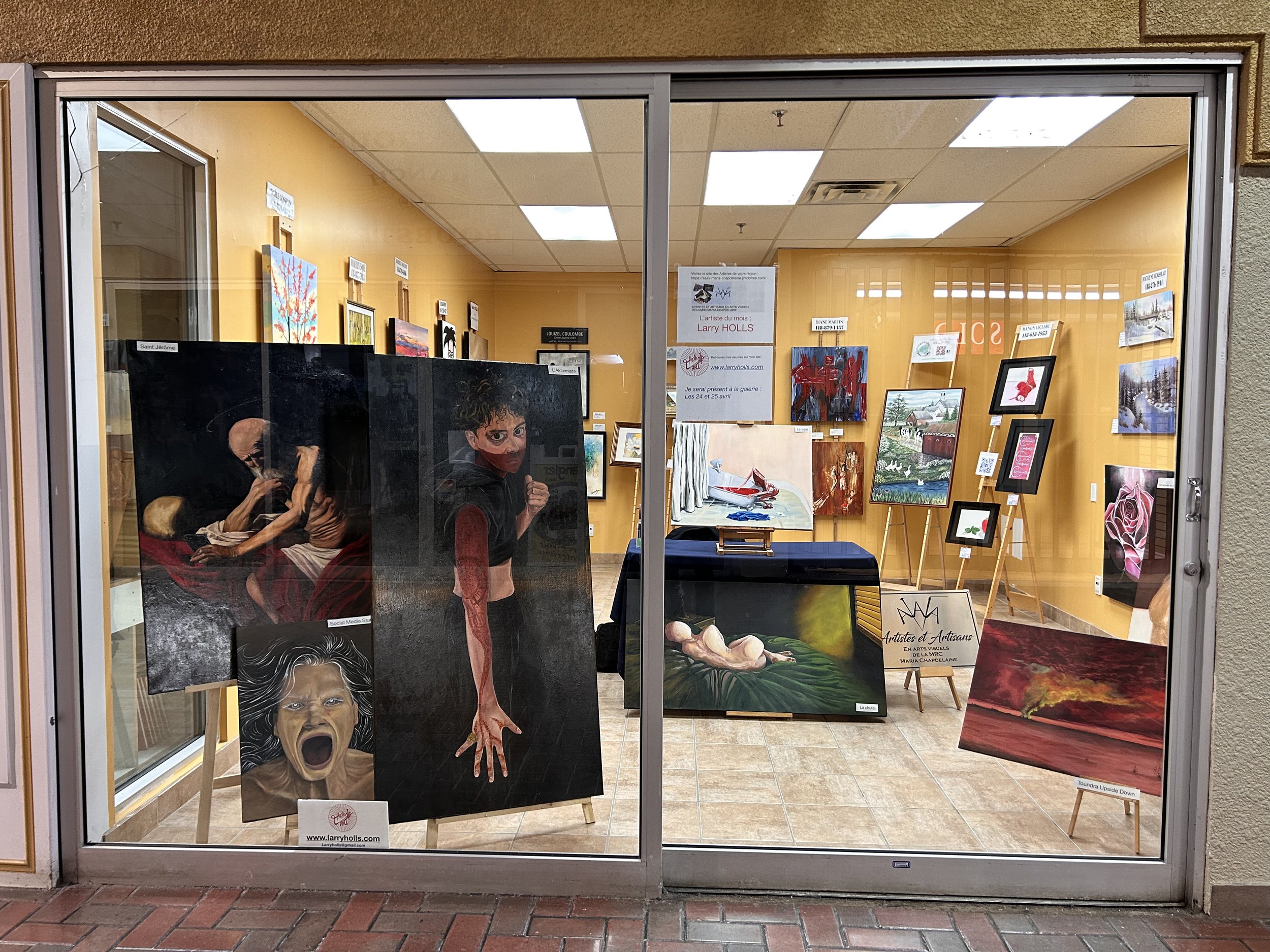 Exposition d'art avec des peintures modernes et classiques dans une galerie, vue à travers la vitrine d'un magasin.