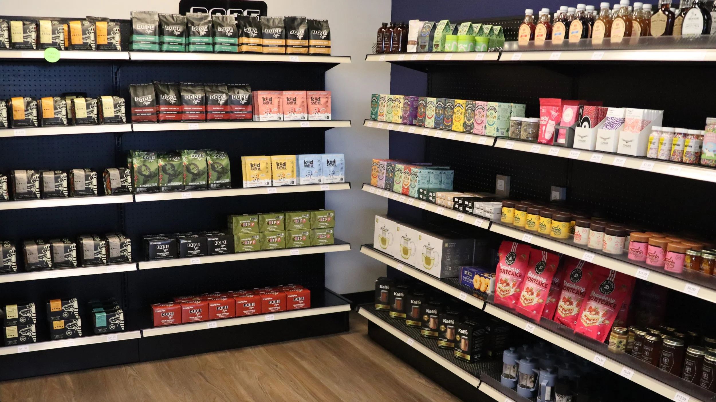 Shelves stocked with various brands of coffee, tea, and related products in a retail store.
