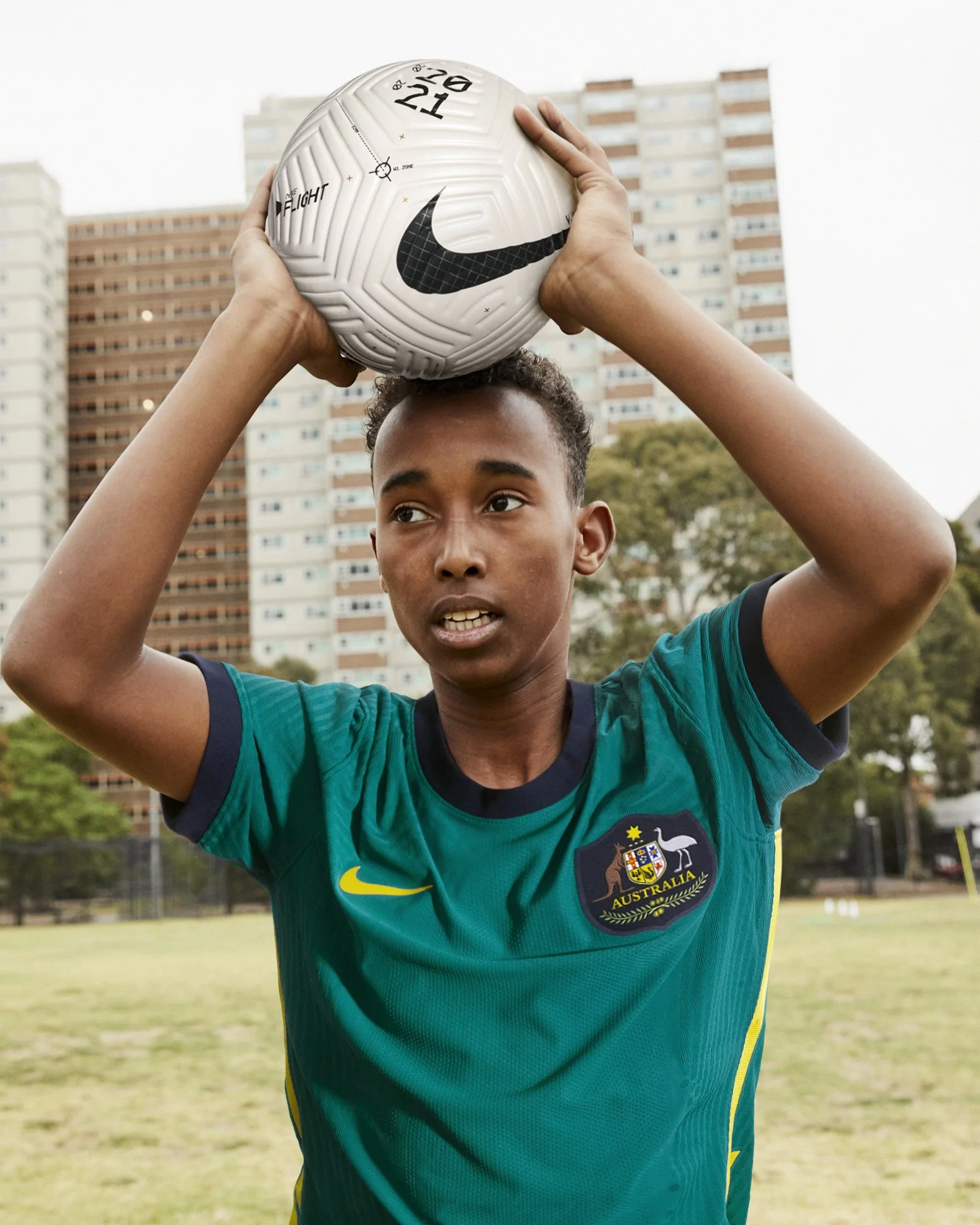 Young soccer player from Australia preparing to throw the ball during a game on an outdoor field.