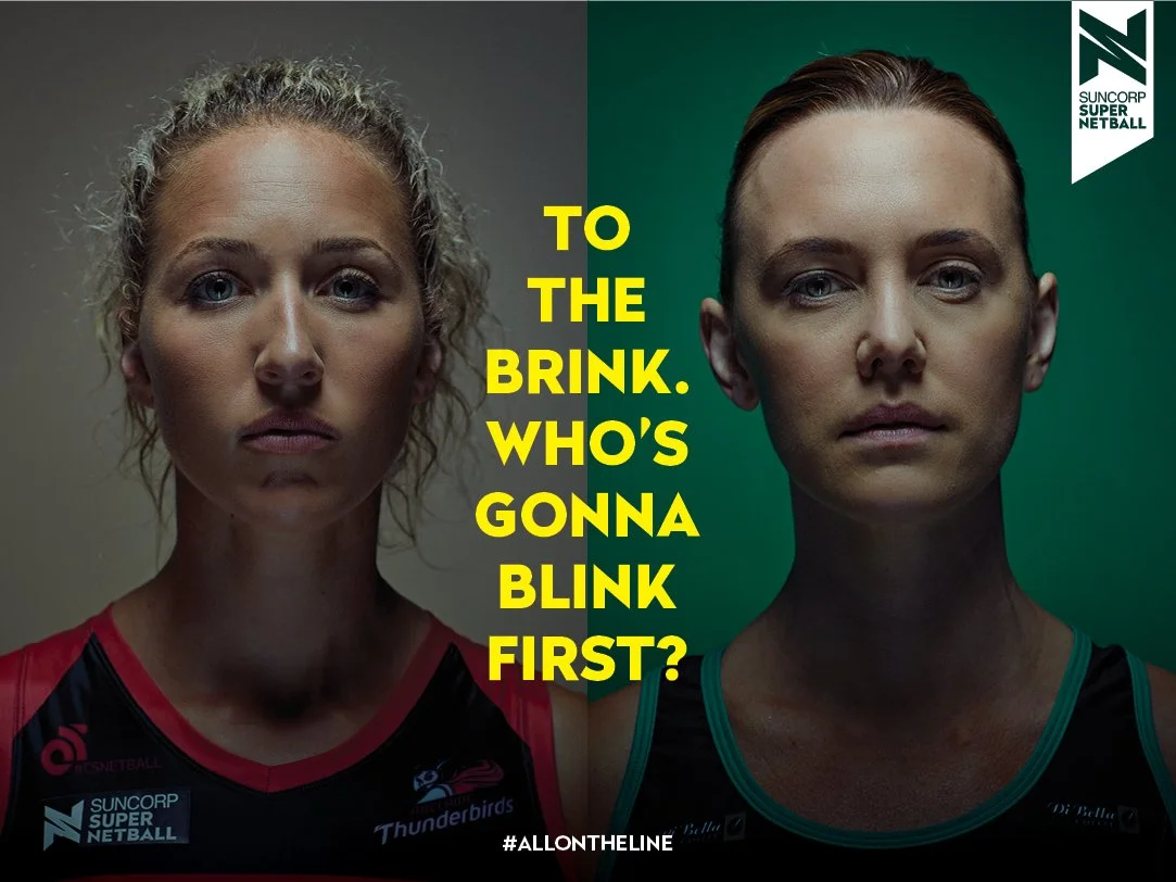 Split photo of two female netball players, one on the left with curly blonde hair and the other on the right with straight red hair, both looking serious. Text in yellow reads "TO THE BRINK. WHO'S GONNA BLINK FIRST?" and a logo in the top right corner for Suncorp Super Netball.