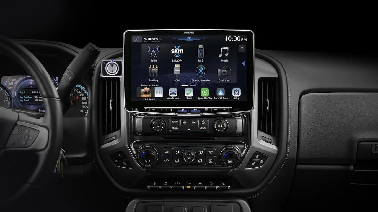 Dashboard of a vehicle with a touchscreen infotainment system displaying music and media options like radio, SiriusXM, USB, Bluetooth, and HDMI, surrounded by climate control buttons.