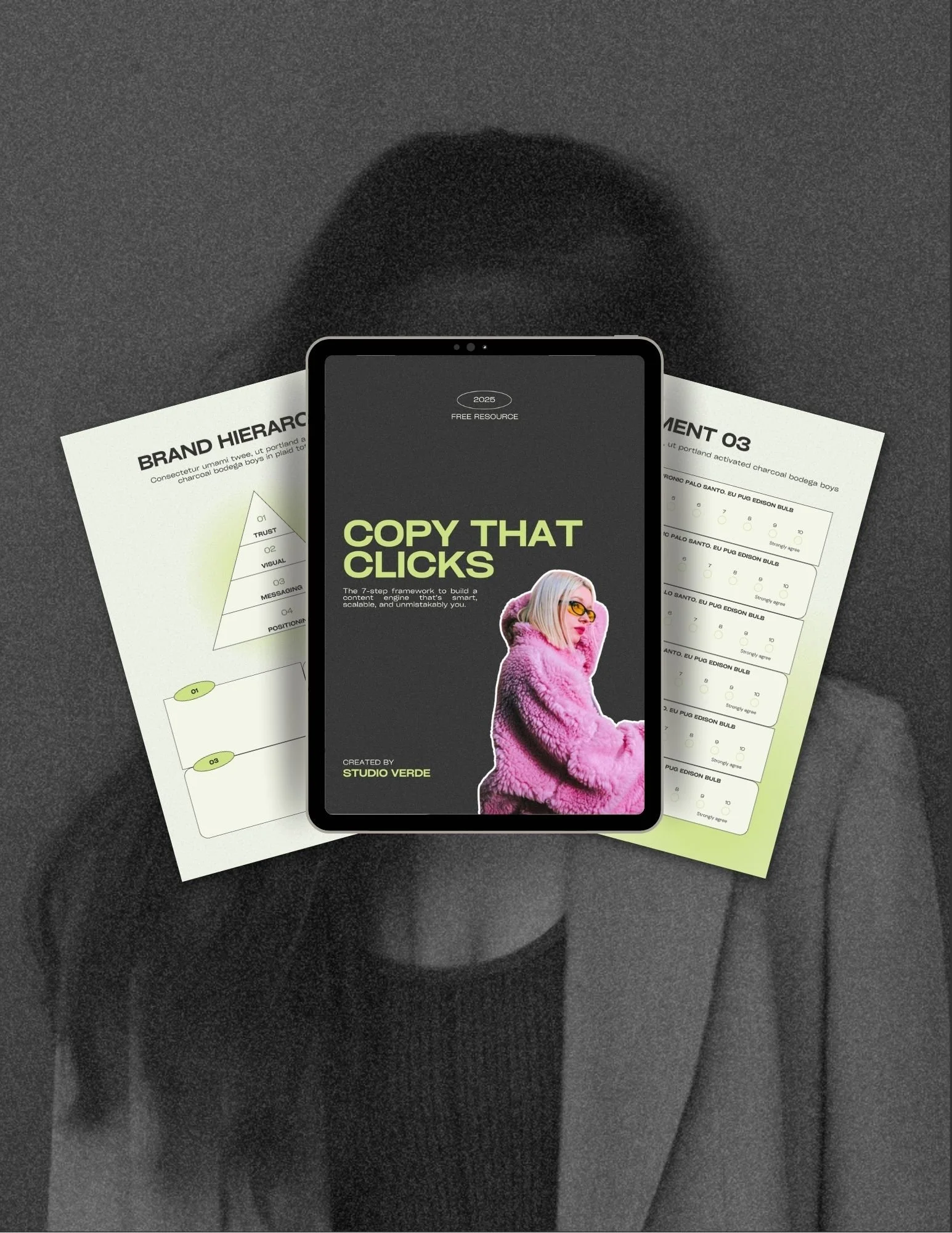 Tablet displaying a digital guide titled 'Copy That Clicks' with a woman in a pink fuzzy jacket on the cover, placed over printed documents on a dark background.