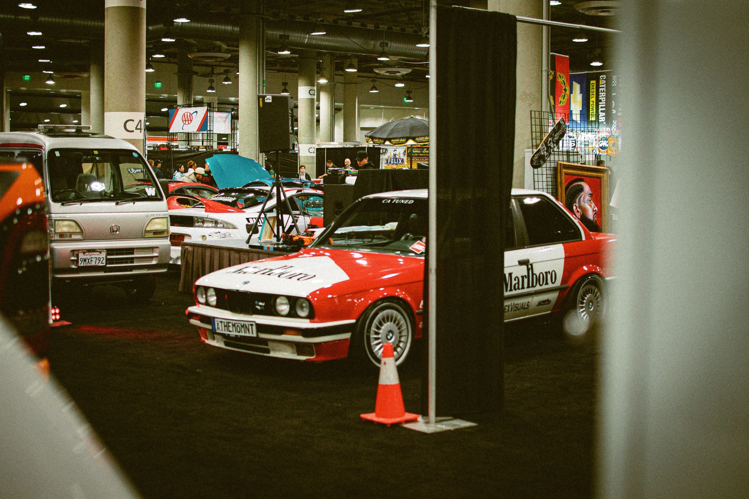 A red and white BMW car with Marlboro racing livery on display at an indoor car show.