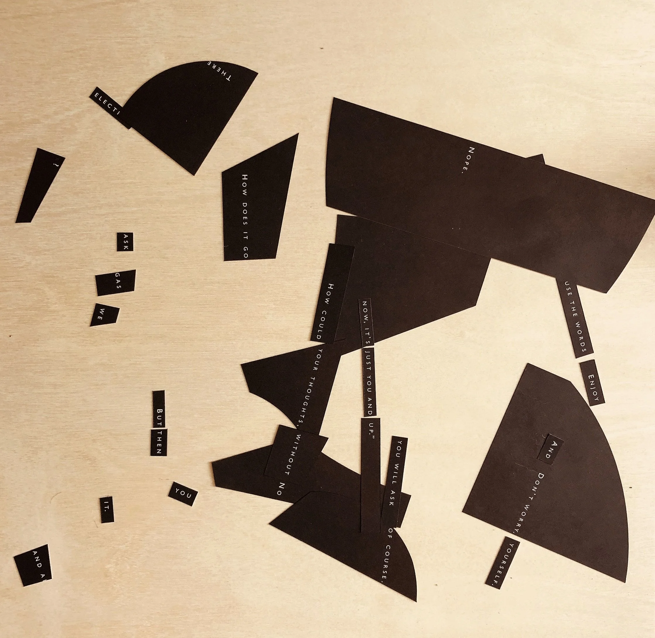 Dark cut-out paper pieces with white text arranged on a light-colored surface. The pieces contain words and phrases such as 'Ask gas,' 'But then,' 'You,' 'It,' 'Nope,' 'Use the words,' 'And don't worry about yourself,' and others, forming a fragmente