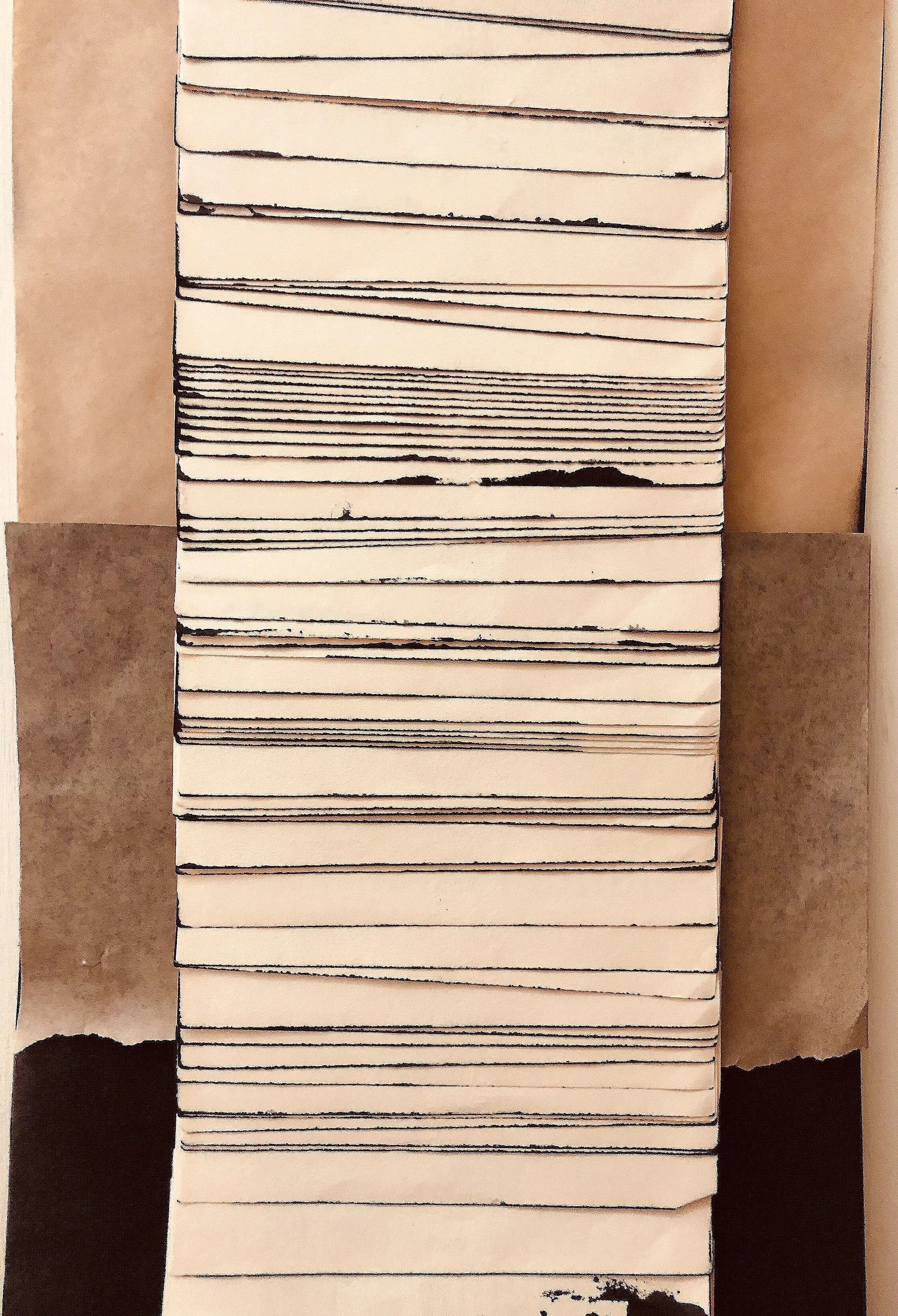 Stack of cardboard boxes with black markings on the edges, placed on a table with brown and beige backgrounds.