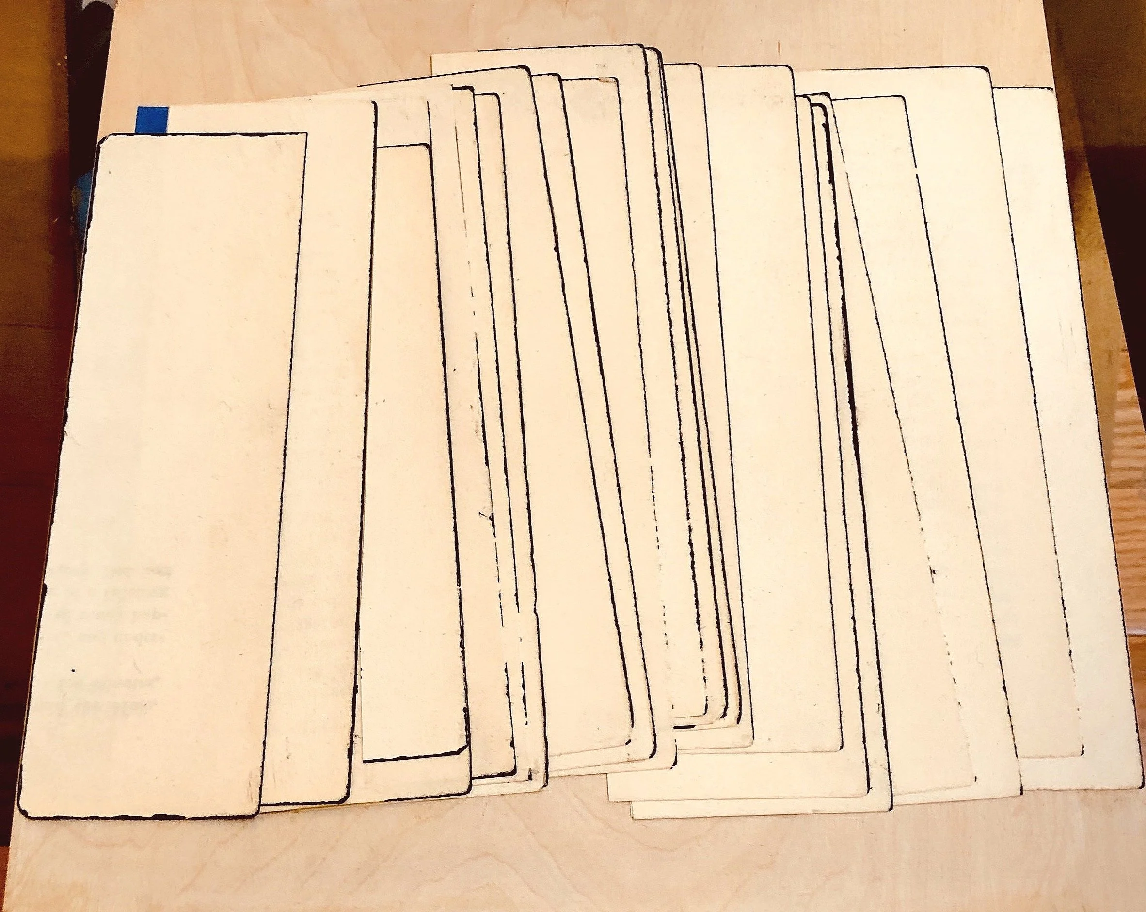 A wooden table with a set of blank white cards that have black outlines of rectangular shapes on them, arranged in a fan-like manner.