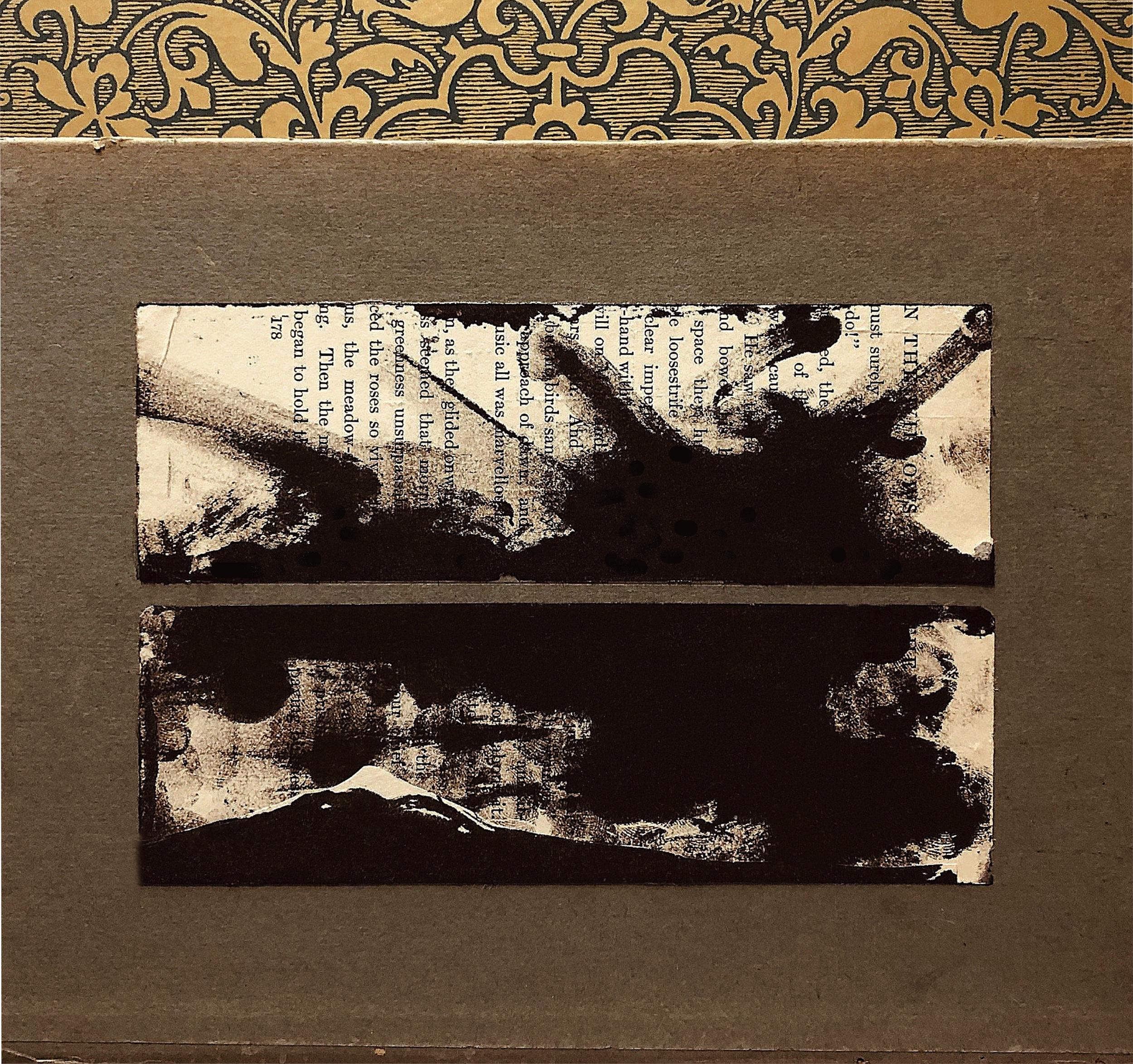 Black and white abstract landscape prints on rectangular paper pieces placed on a brown background, with visible text and textures.