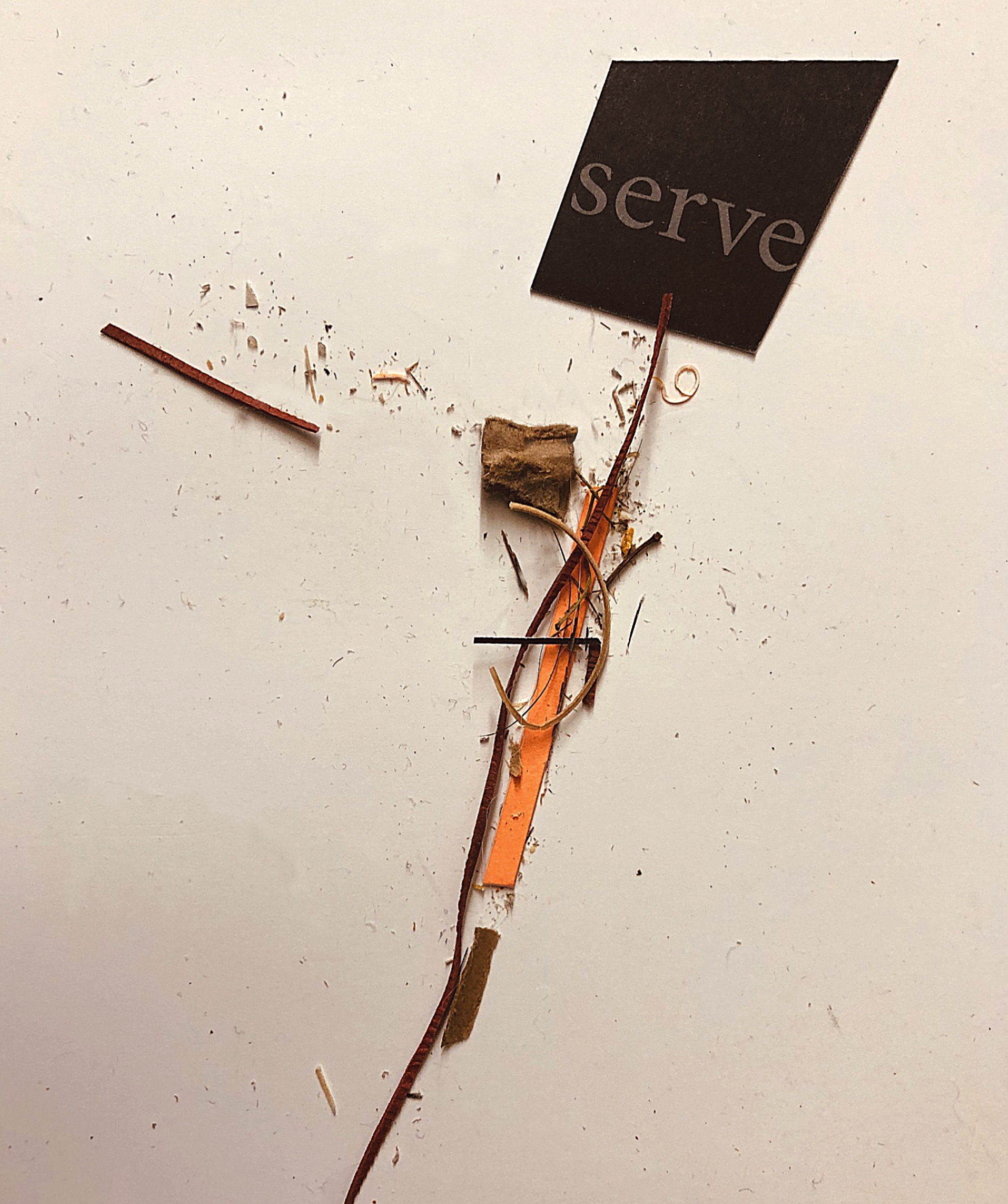 Disassembled electronic device with a black square that has the word 'serve' written on it, various small pieces of wires, a piece of cardboard, and other small components scattered on a white surface.