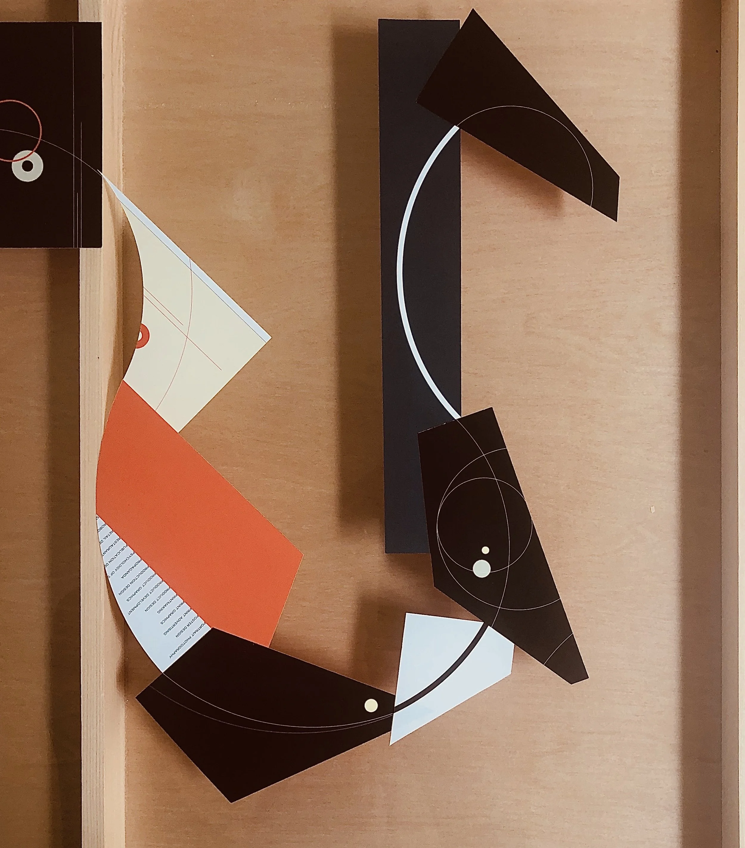 Abstract wall art with geometric shapes and lines in black, white, red, and orange on a wooden background.