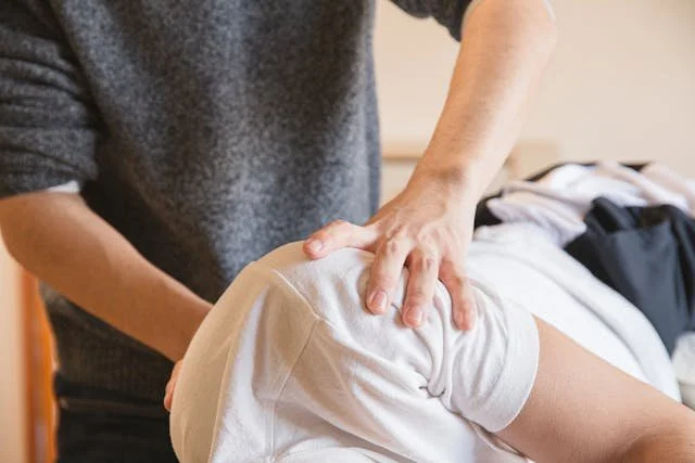 A person receiving a massage on their thigh while lying on a bed or massage table.