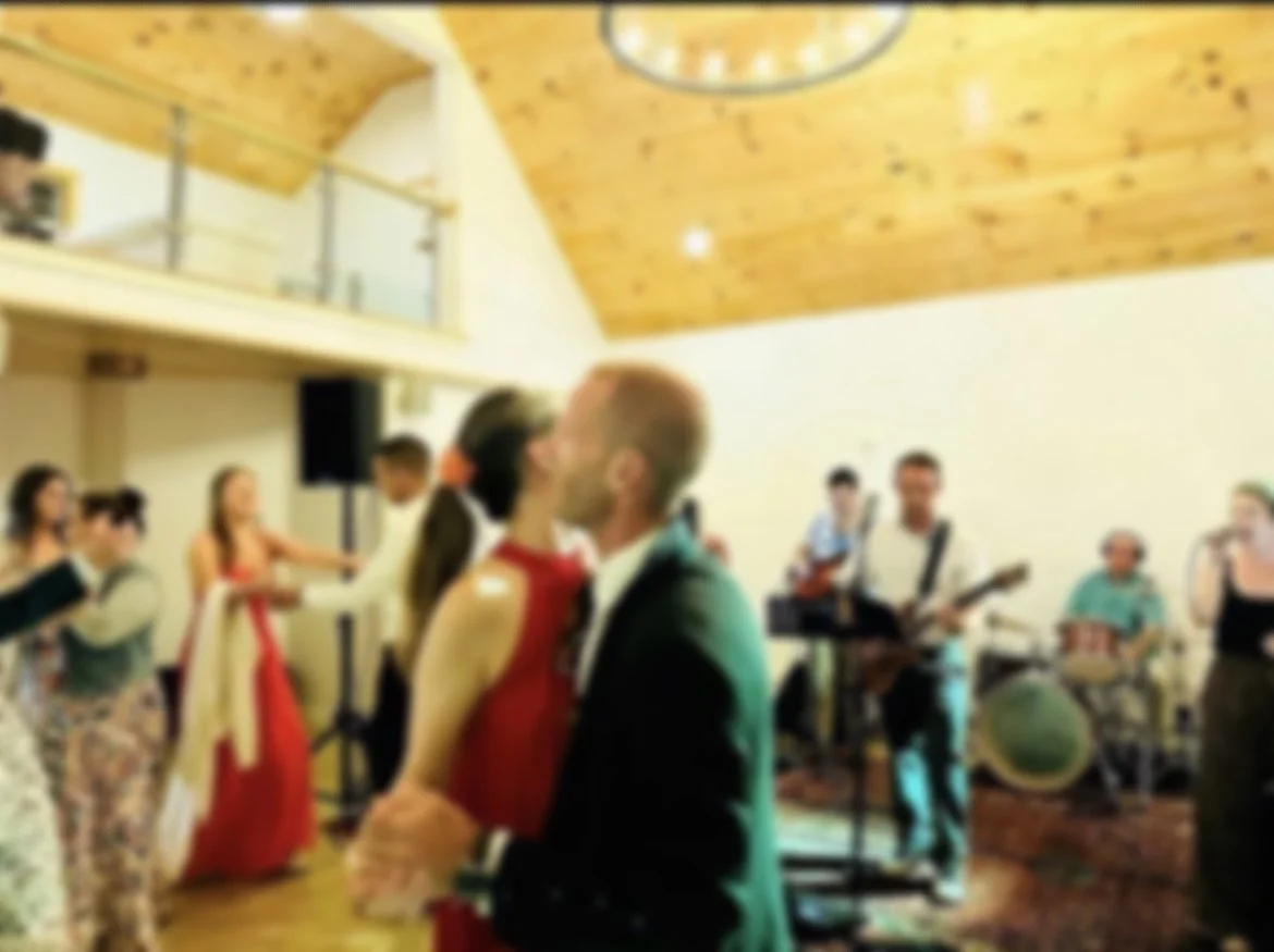 Couple dancing at a lively indoor event with live band playing in the background.