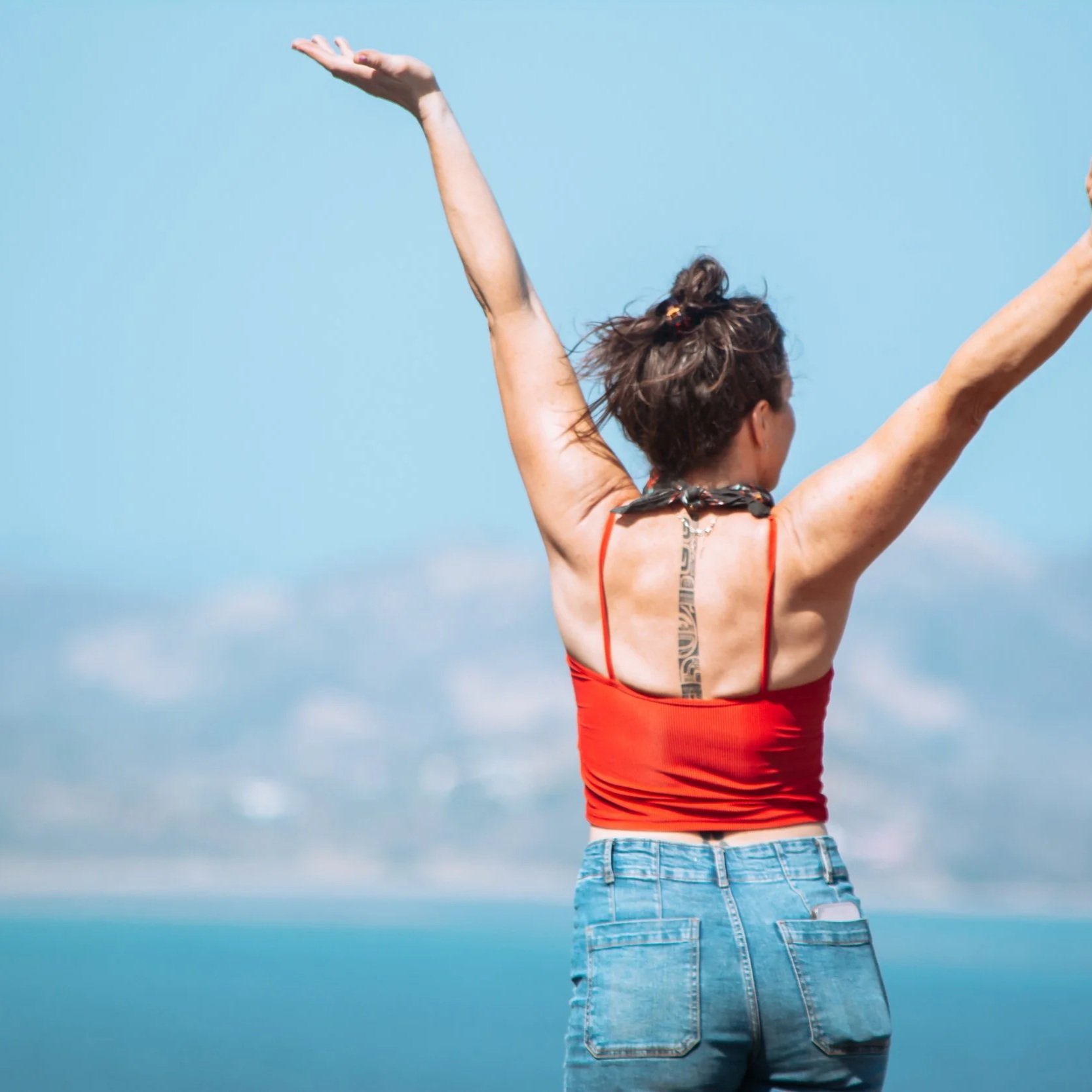 Jessica Sell Chambers is standing on top of a mountain in costa rica with her arms outstretched