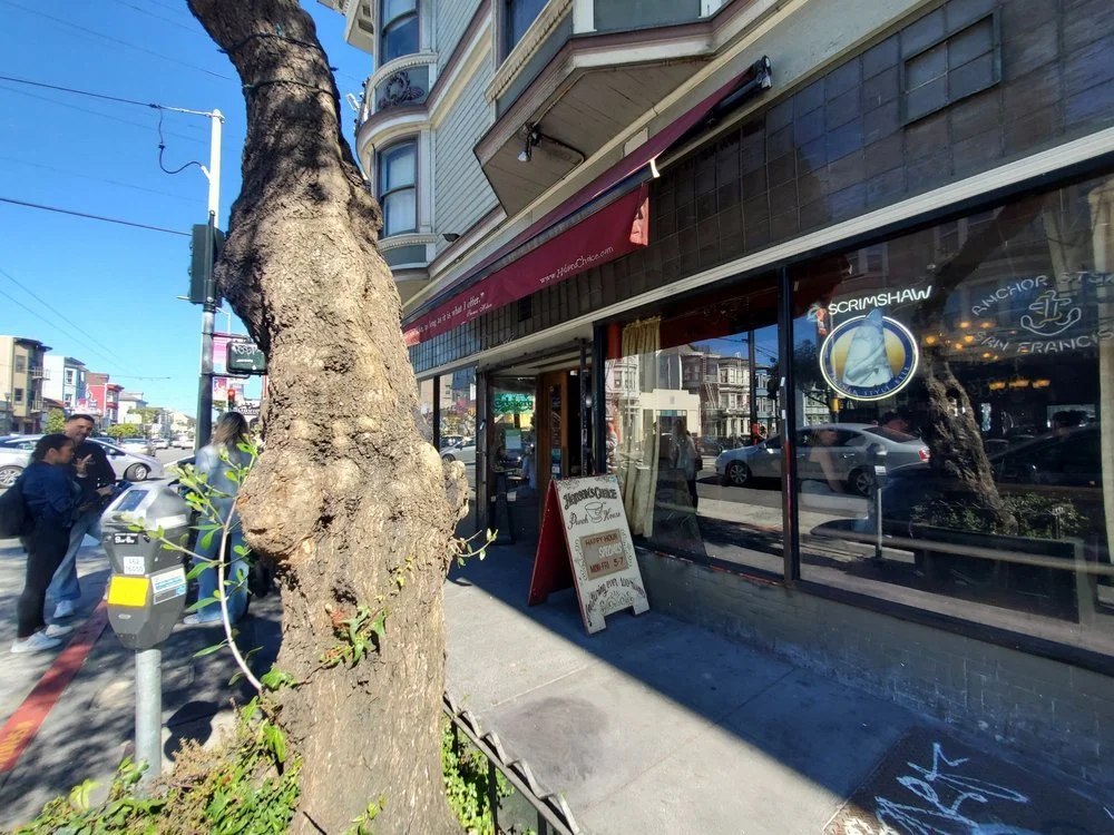 The Hobson&rsquo;s Choice corner storefront at 1601 Haight with its burgundy awning and Punch House sandwich board, seen from the sidewalk on a sunny day.