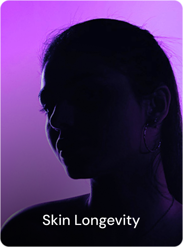 A smiling man in a light blue shirt eating salad outdoors with a bowl of fresh vegetables, sunlight filtering through trees in the background.