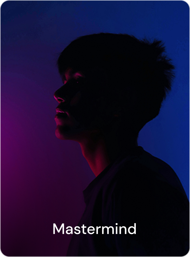 Person standing on a wooden dock looking at a calm lake surrounded by snow-covered mountains during sunset.