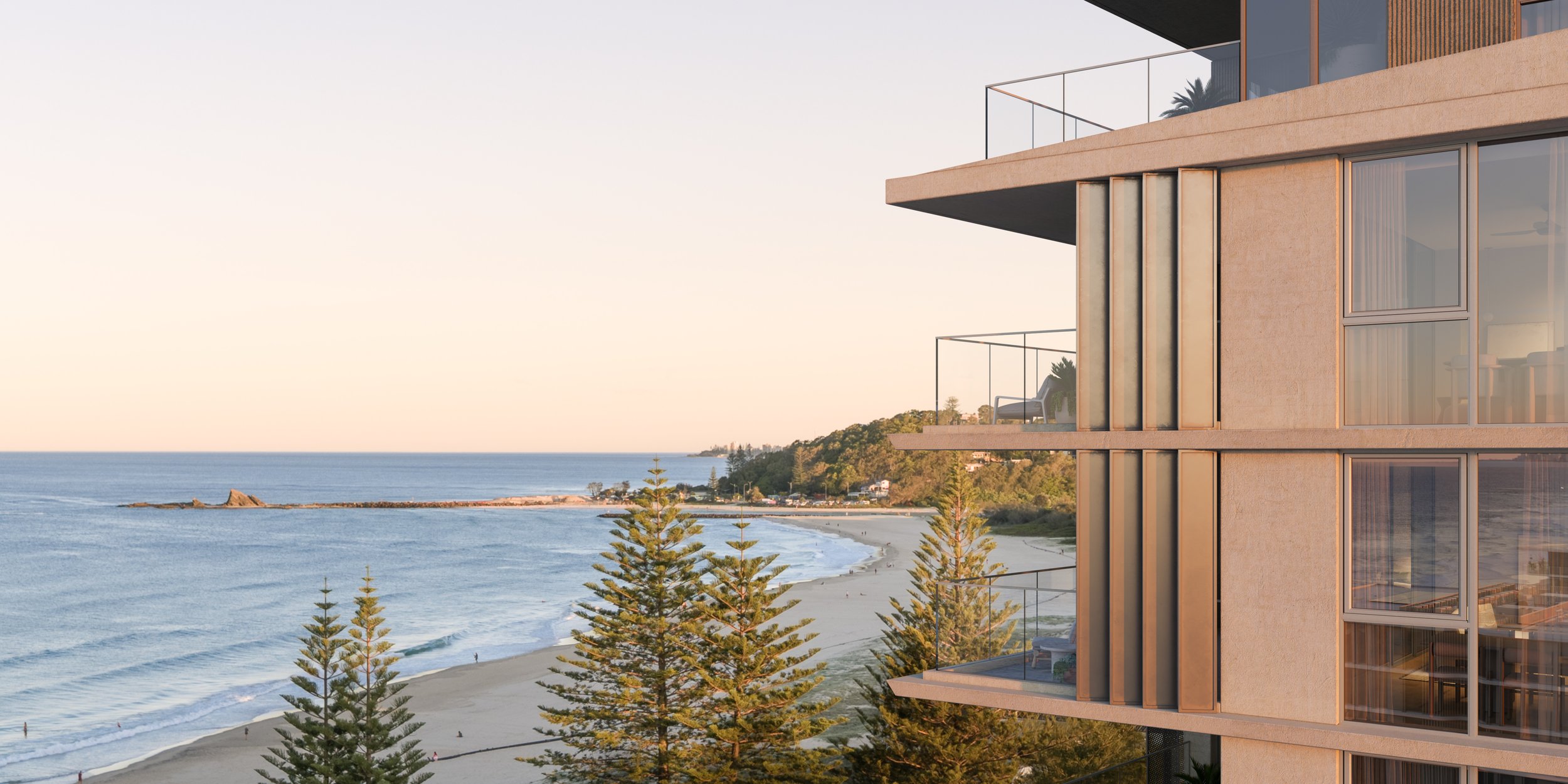 Modern beachfront building with balconies overlooking the ocean, sandy beach, and pine trees at sunset.