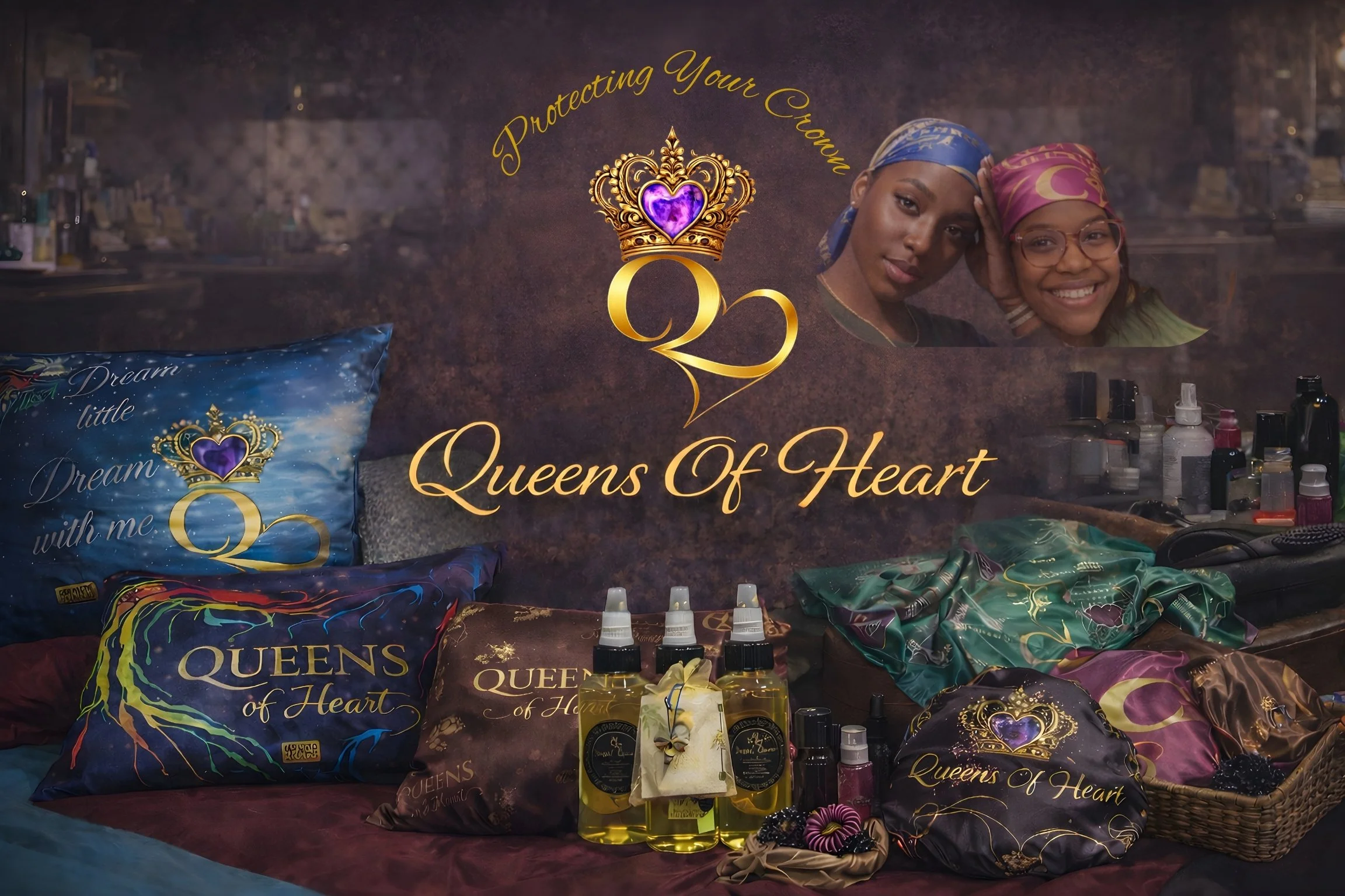 Display of Queens of Heart branded pillows, bottles, and accessories on a table, with a backdrop featuring two women and a crown logo with purple heart in the center, and the words 'Protecting Your Crown' and 'Queens Of Heart'