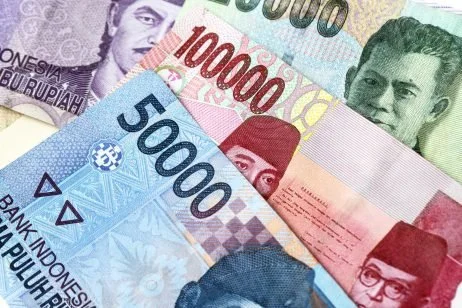 Several Indonesian banknotes of different denominations, including 100,000, 50,000, and 10,000 rupiah.
