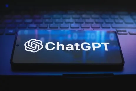 Smartphone displaying the ChatGPT logo and name on a keyboard background.