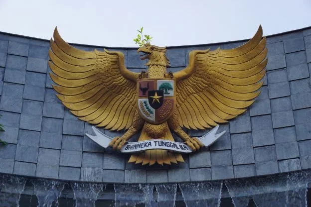 Garuda Pancasila, the national emblem of Indonesia, mounted on a wall with a water feature below.