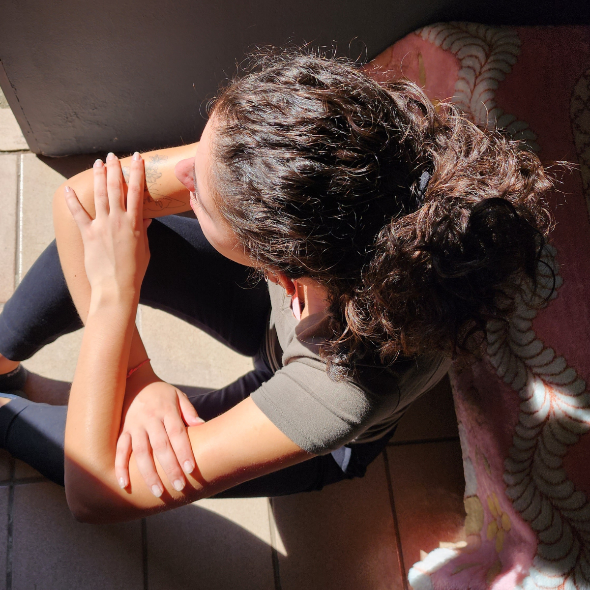 A woman sitting curled over with her head down, representing the exhaustion and self-erasure that many women with ADHD experience after years of people pleasing and masking.