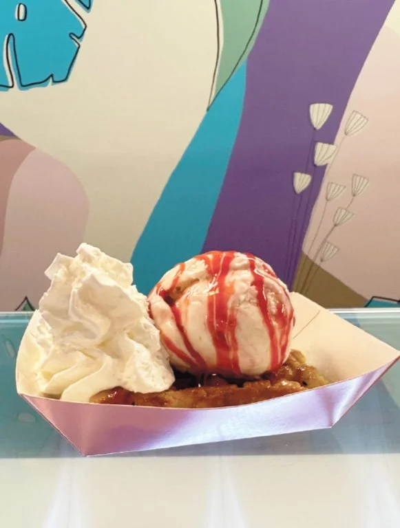Ice cream sundae with whipped cream and cherry on top, served in a pink paper boat