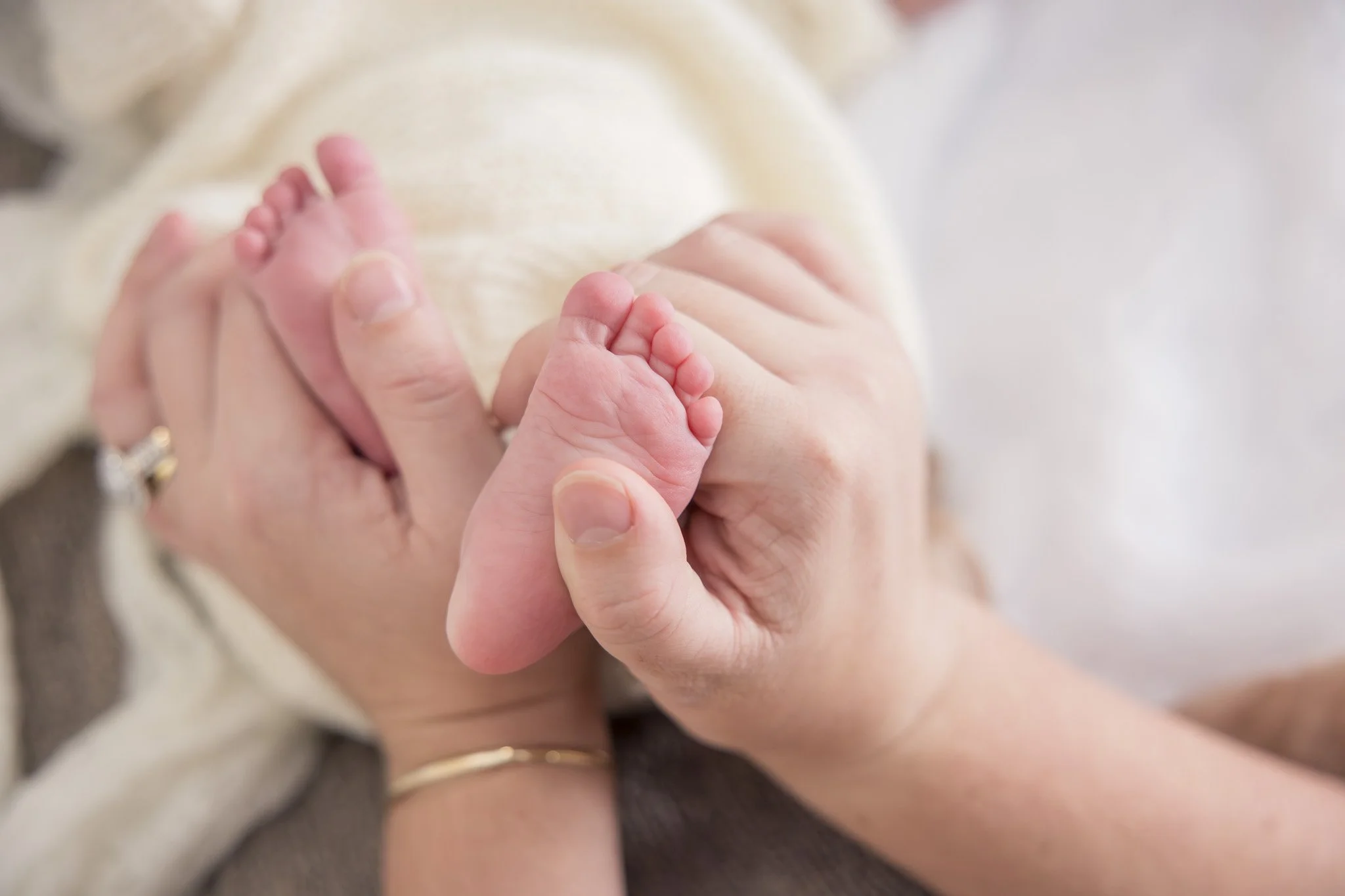 Close-up of a baby's tiny hand grasping an adult's finger, with a blurred background.