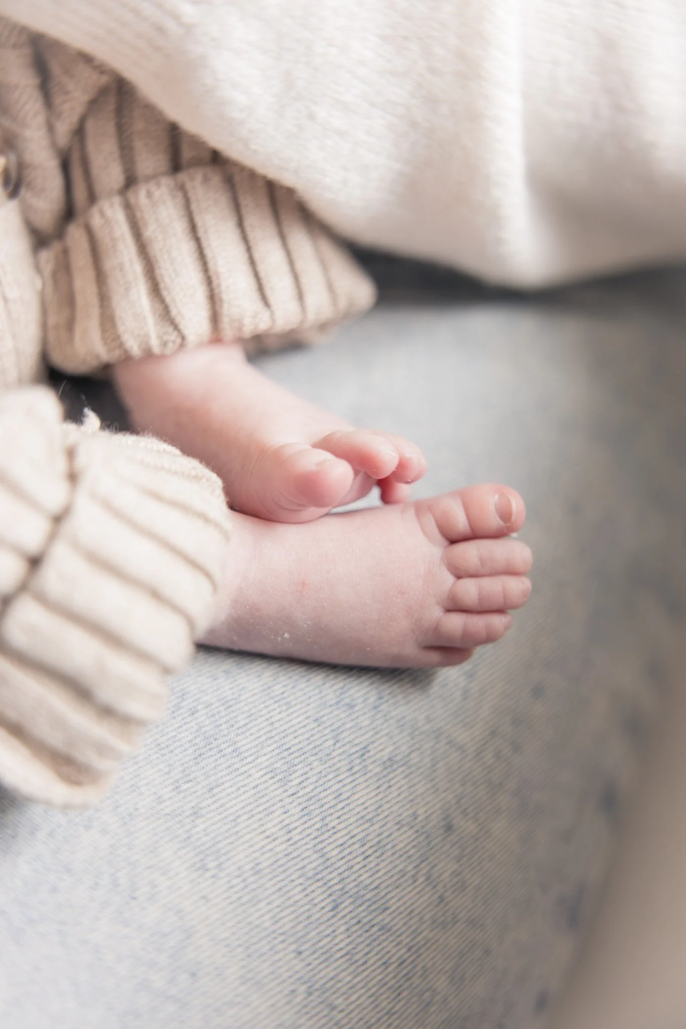 Close-up of a baby's hand resting on an adult's hand, with the baby's clothing and adult's clothing visible.
