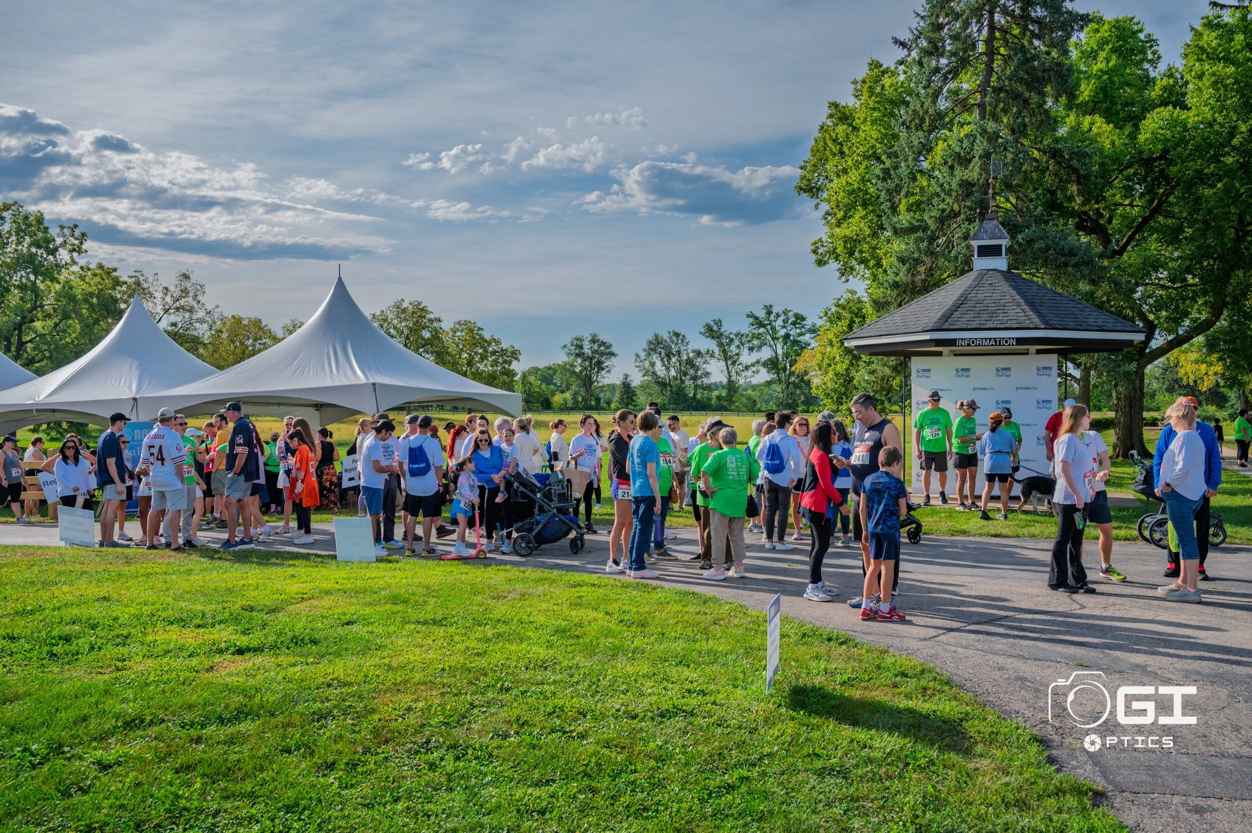 Crowd gathered under event tents at a charity walk, covered as part of an event media package