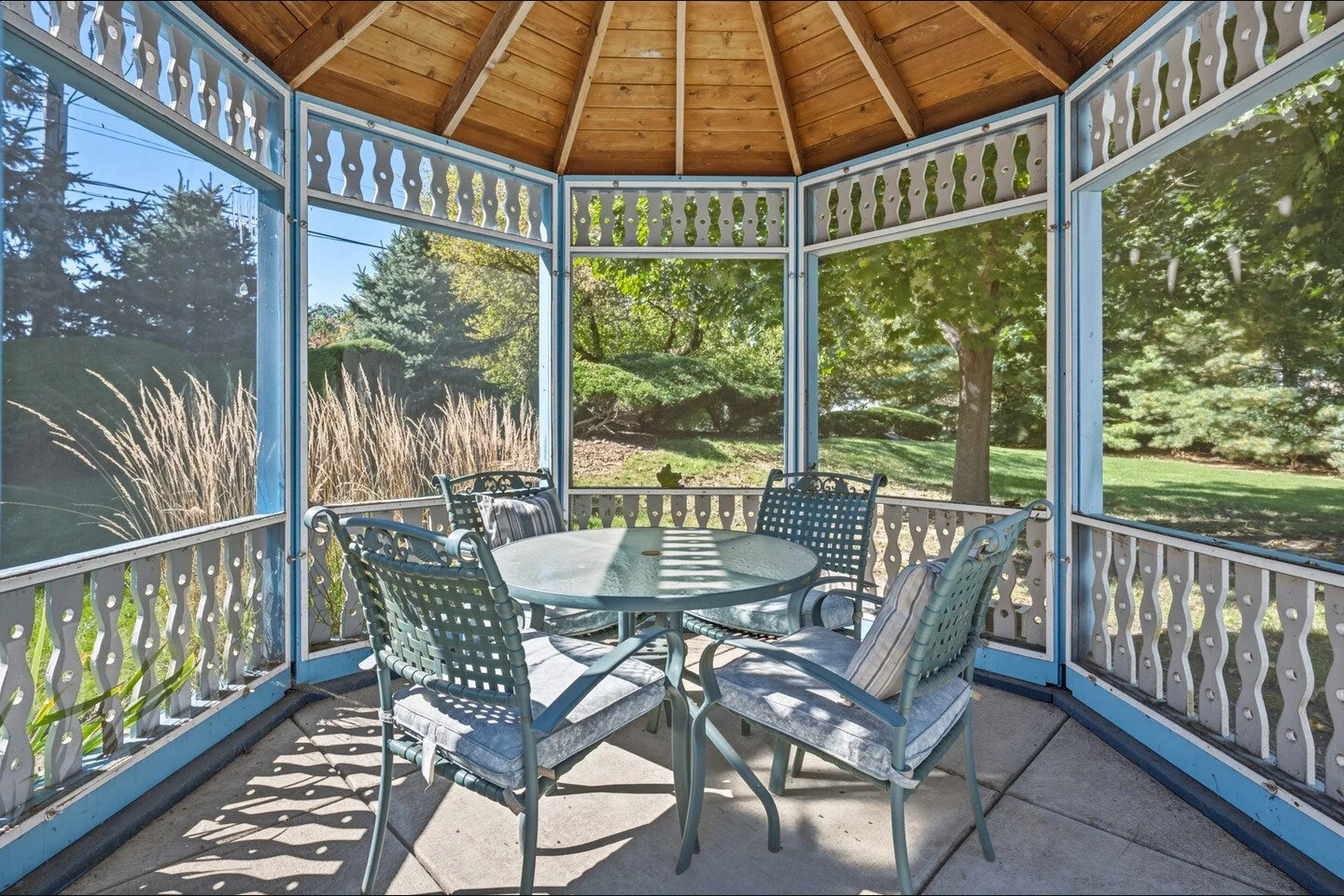 Inside the screened gazebo looking out through the screens into mature trees.jpg