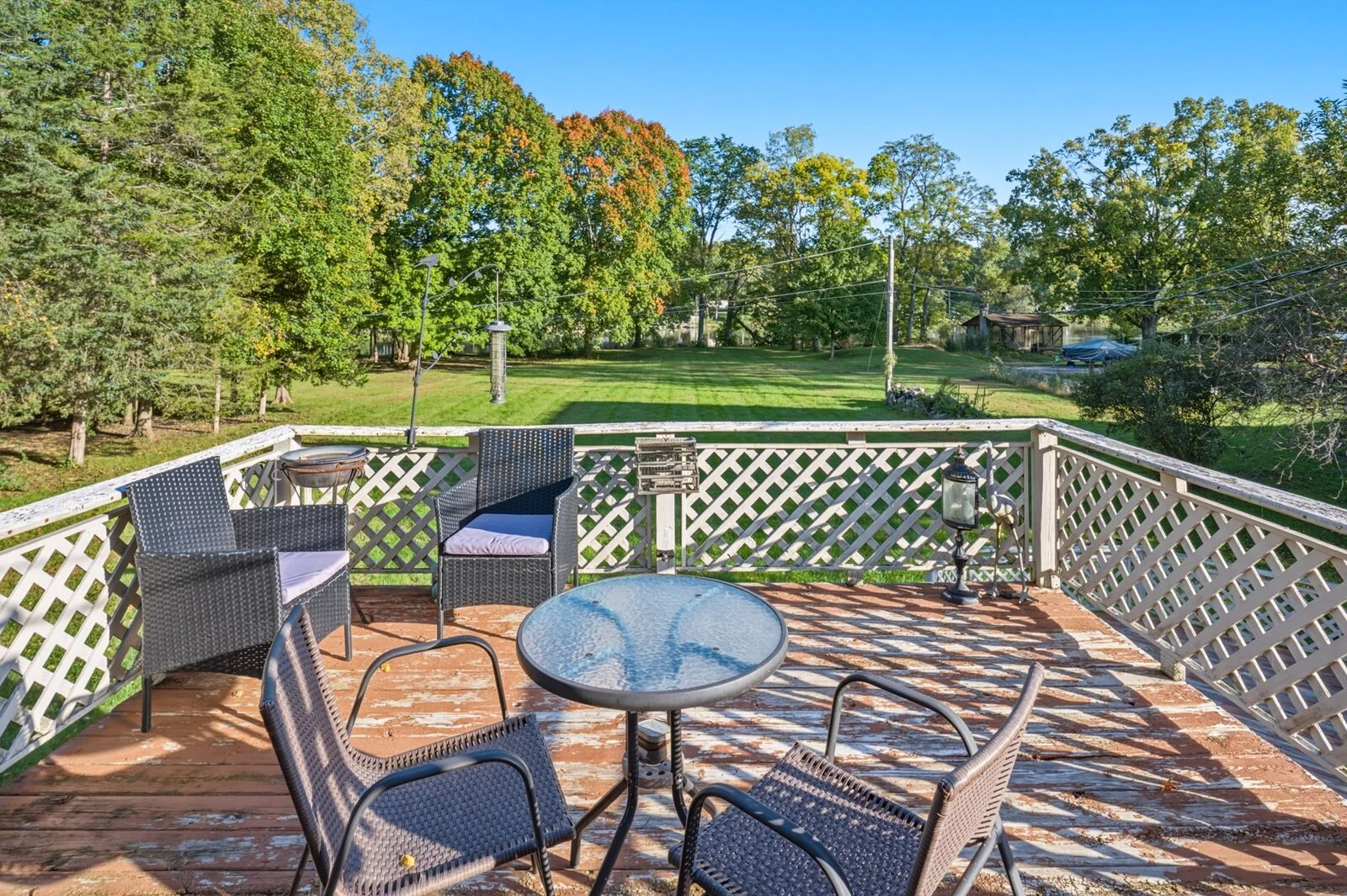 Deck with table and chairs overlooking the back lawn and tree line.jpg