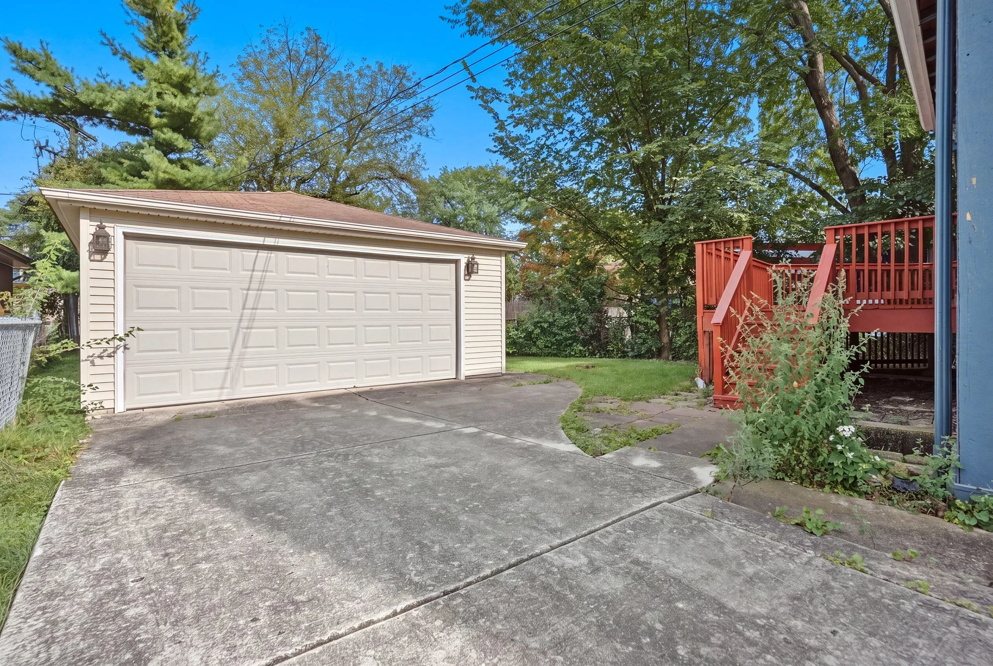 An empty concrete driveway running to a detached two-car garage, with no vehicles parked in the frame.
