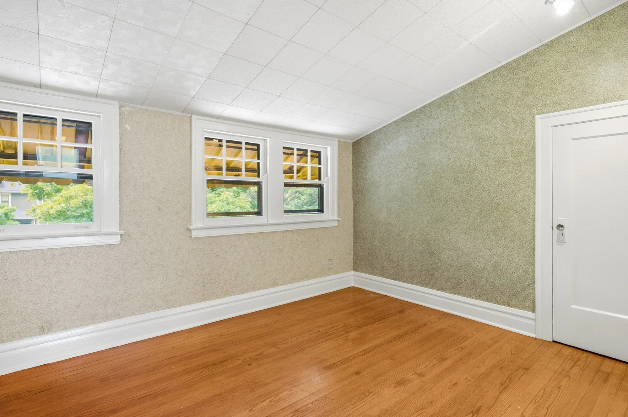 Second-floor bedroom with a double window where the trees outside are still visible instead of blown out to white.