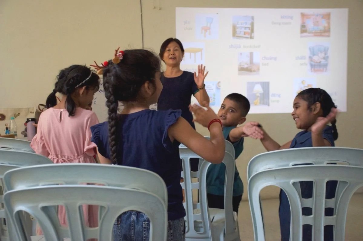 Children waving their hands during a Mandarin lesson in Banting, Selangor