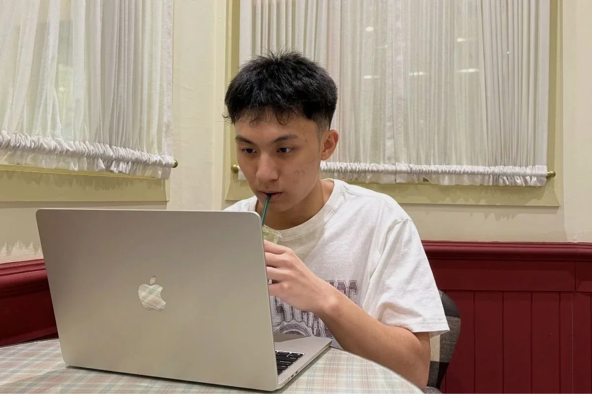 A student drinking matcha while attending an online Mandarin class on a laptop