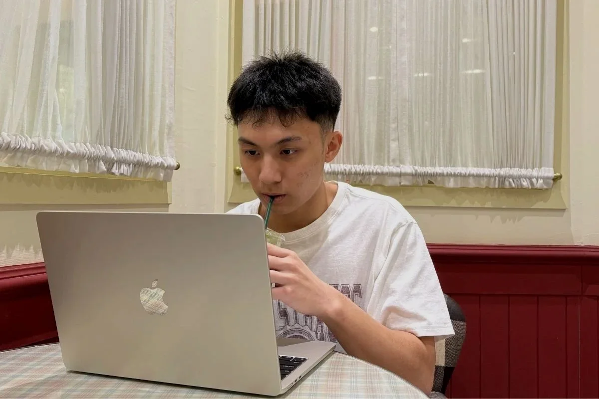 Student attending an online Mandarin class on a laptop in a cafe