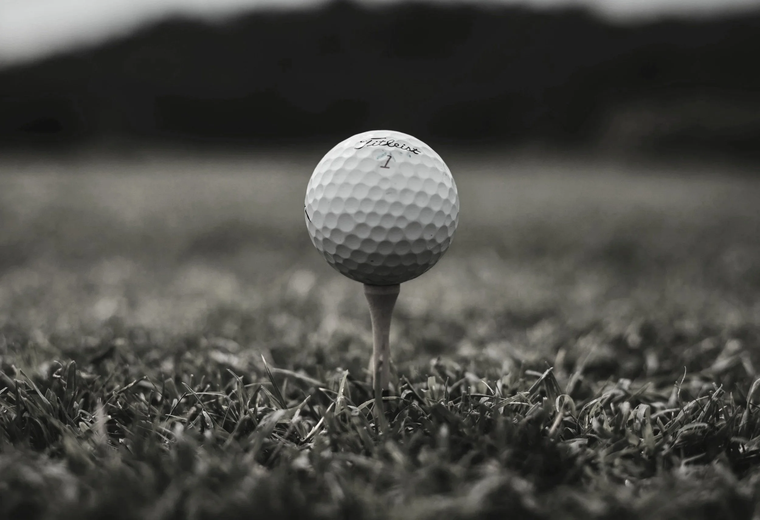 A close-up shot of a golf ball teed up on a grassy golf course.