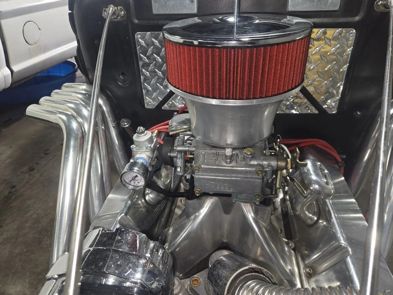 hot rod with holley carburetor and velocity stack and a fuel pressure regulator setup.