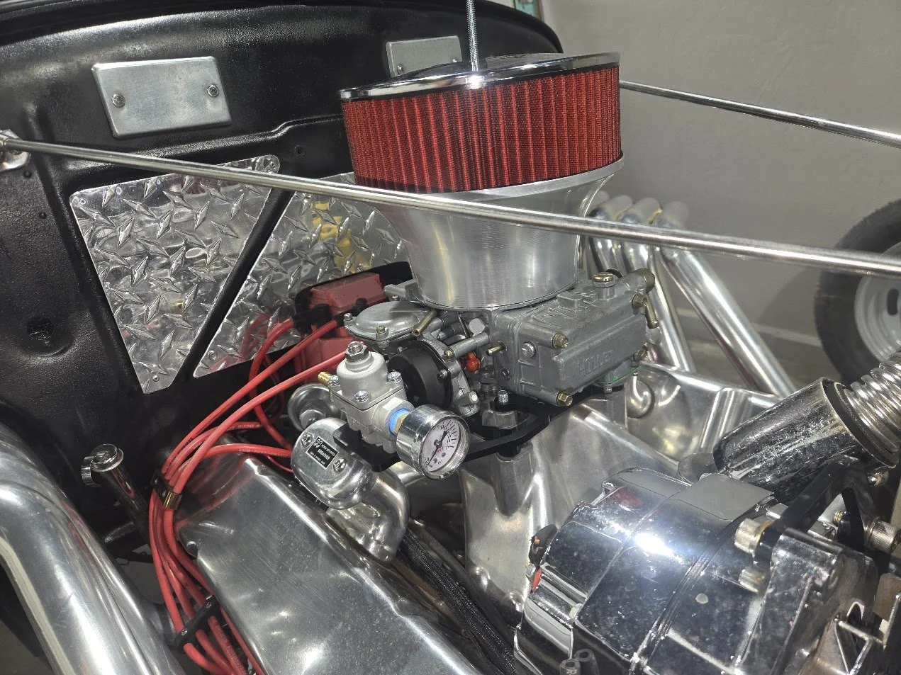 hot rod with holley carburetor and velocity stack and a fuel pressure regulator setup.