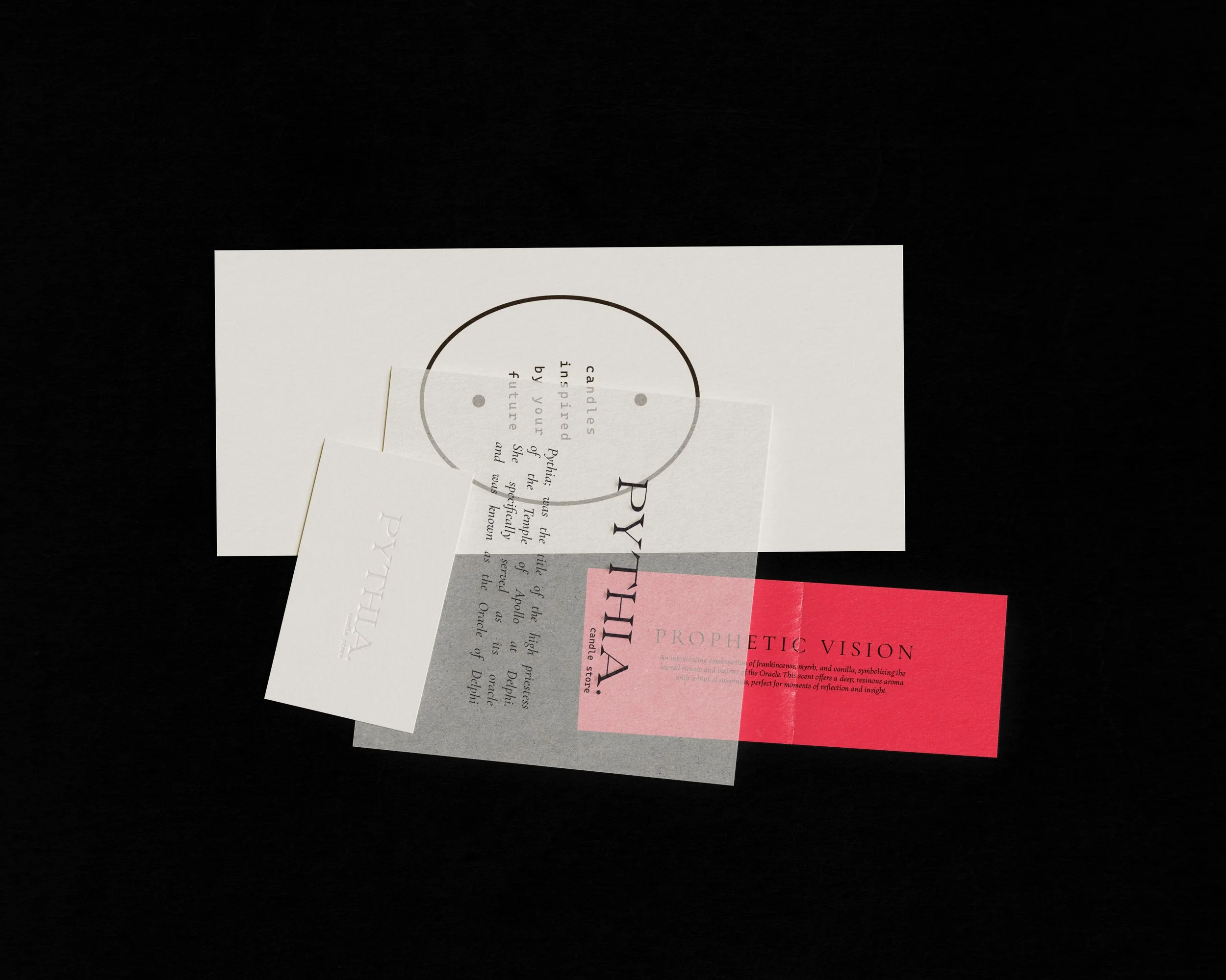 A cube-shaped package with a pink and beige design, labeled "PYTHIA" and "Delphic Whisper," resting on a white surface with sunlight and shadows on the ground.