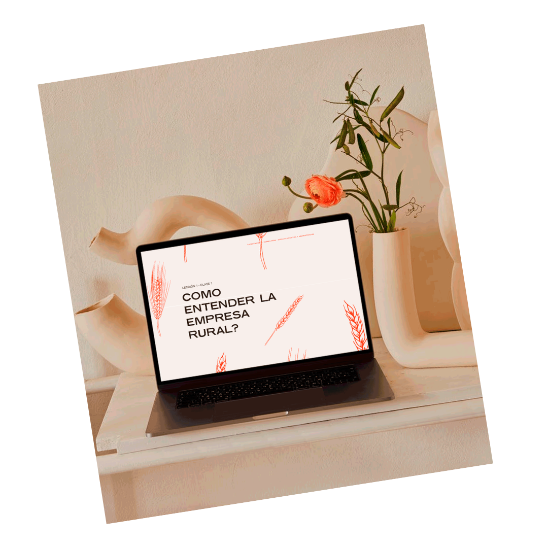 A laptop on a white table displays a presentation slide in Spanish titled '¿Cómo entender la empresa rural?' with a minimalistic design of red wheat stalks.