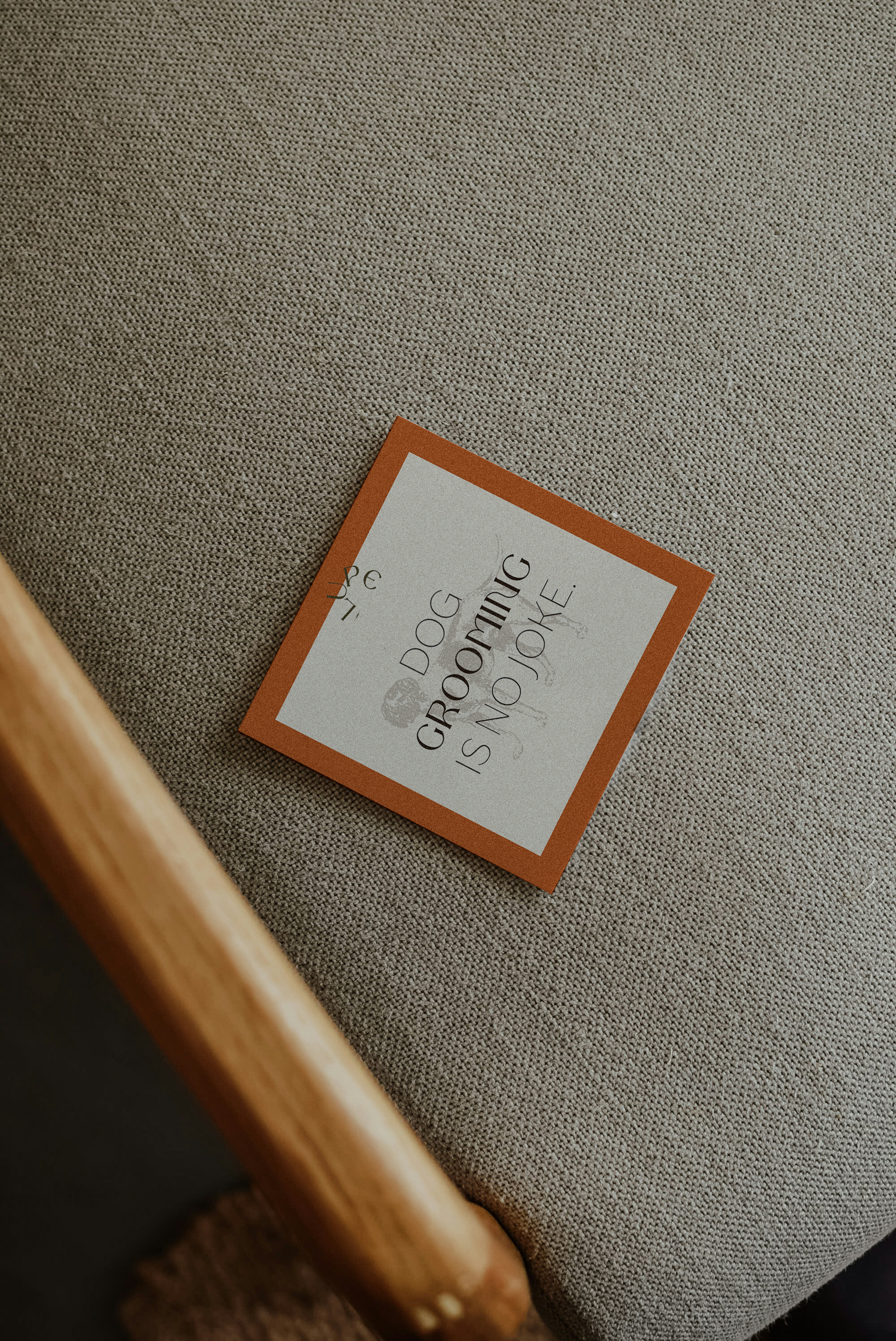 A small square paper with a red border lying on a beige fabric surface. The paper reads 'GROOVING IS NO JOKE' with some smaller, less visible text and a faint skull illustration.