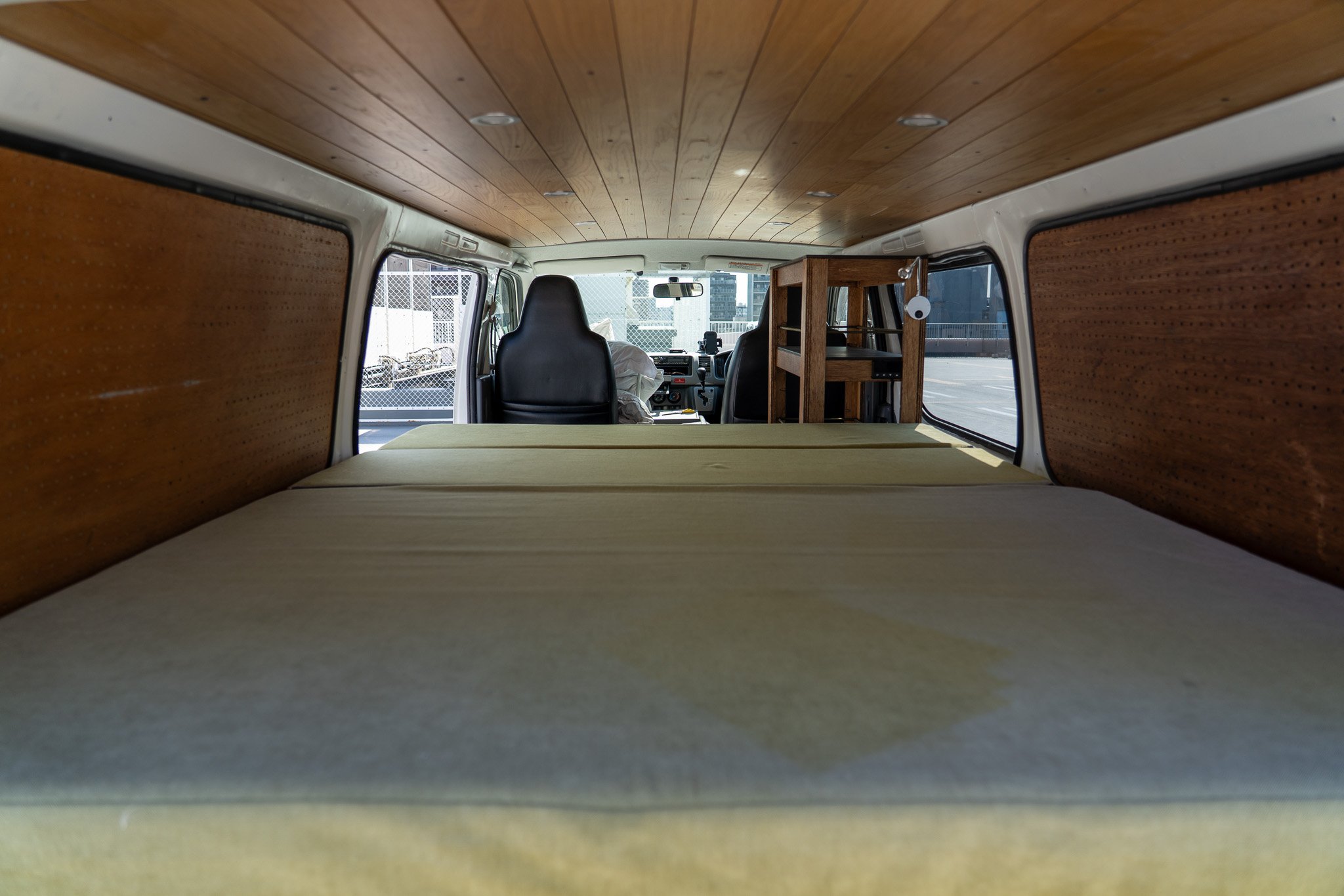 レトロなキャンピングカーの内部、後方から見た寝床スペース。木製の天井と壁、マットレスと前席の運転席が見える。」}}/******/json-schema-from-ImageAltText വൈറამდე: 40/40niki_user: つの車の内部を写した写真です。車の後部にマットレスが設置されているのが見えます。前方には運転席があり、その前には木製の棚とモバイルデバイスが置かれた小さな机があります。車内は木製の天井と壁で囲まれています。}】} そのままご質問ください。】}】【User: 車