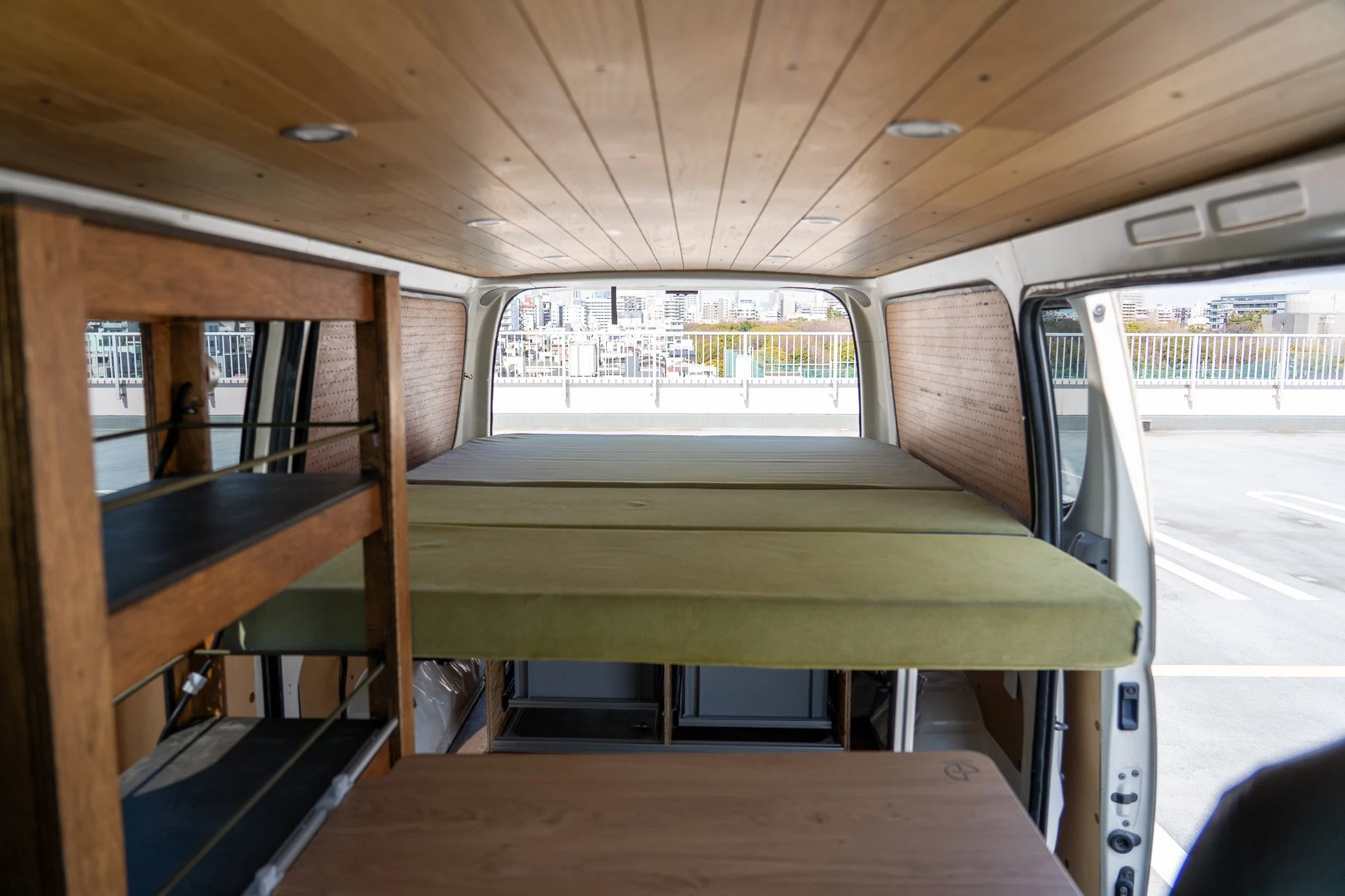 Spacious campervan interior with flat double bed and wooden panel finish
