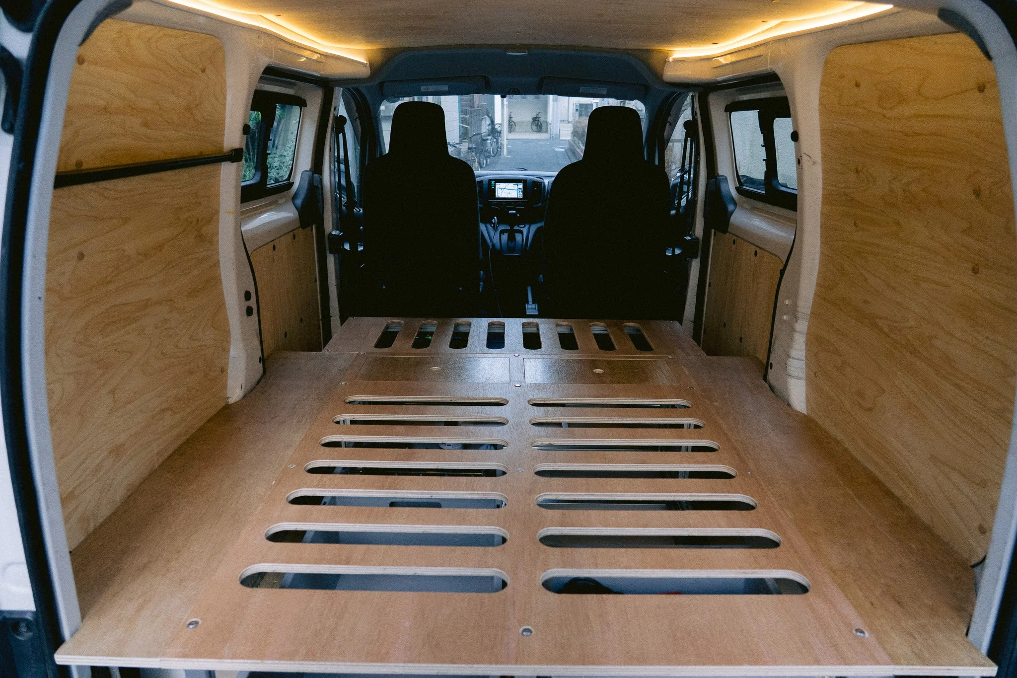 木製の仕切りと床が設置された、空のバンの車内