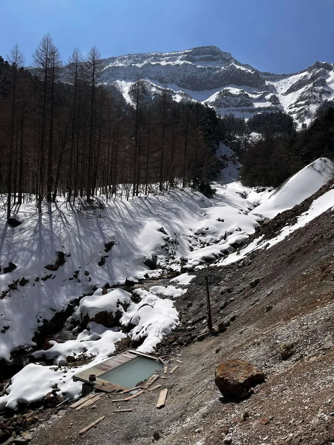 Open-air onsen hot spring with a snowy mountain view in the Japanese mountains