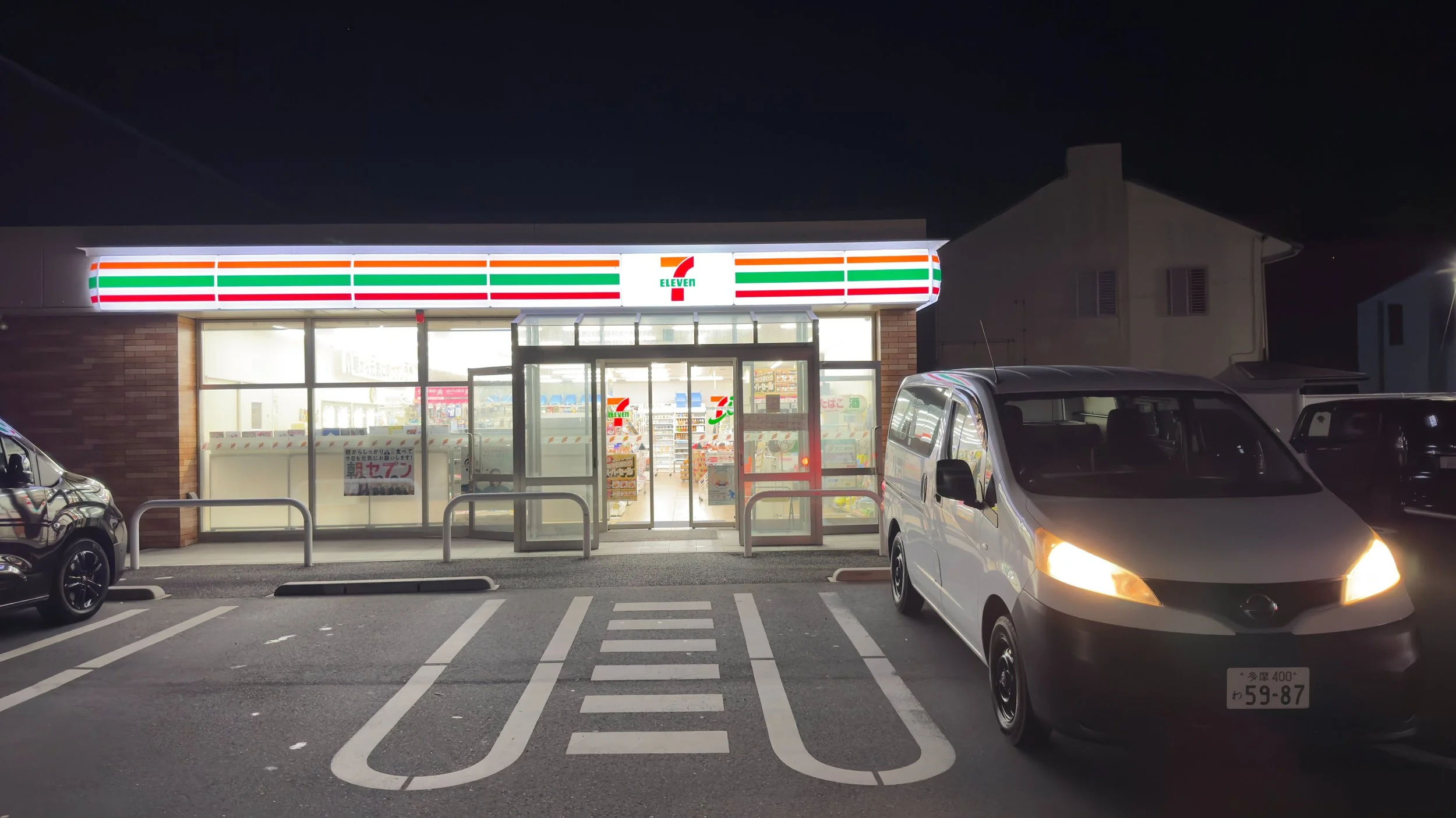7-Eleven convenience store at night next to a campervan in Japan