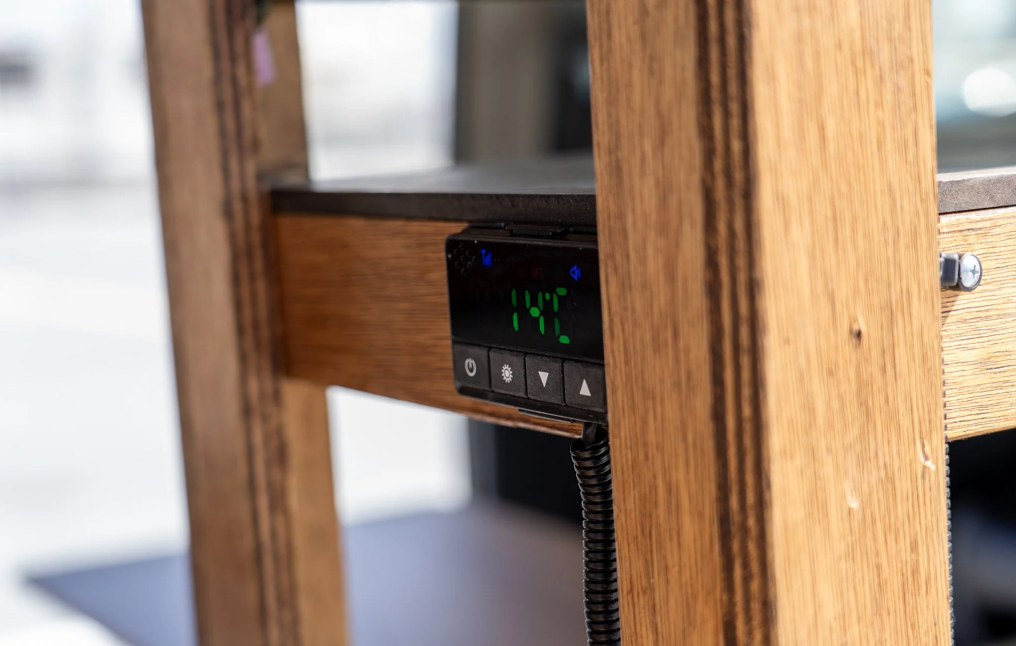 木製の家具の側面に取り付けられたデジタルコントローラーと温度計、画面に14°Cと表示されている