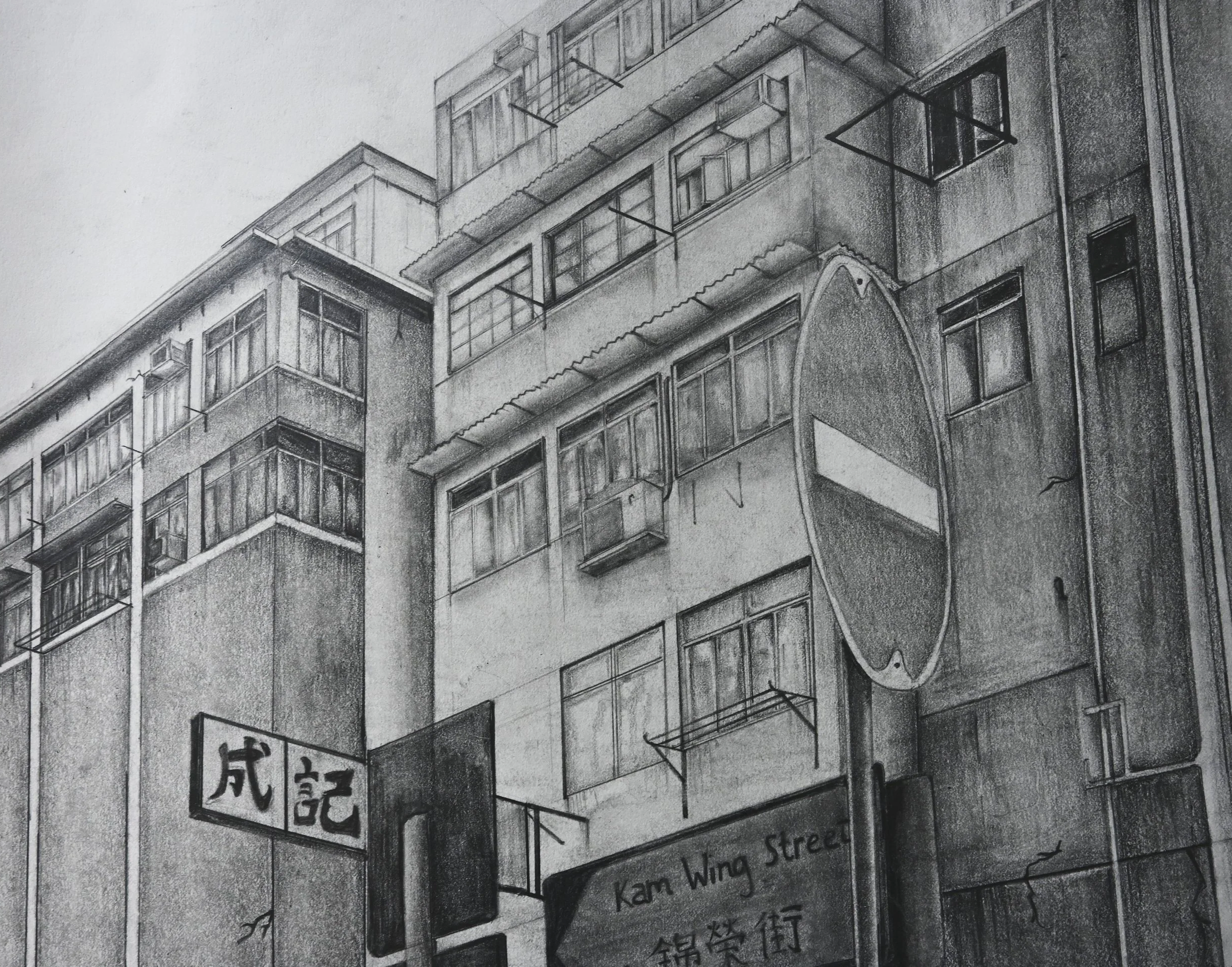 A black and white pencil sketch of a city street scene showing multi-story buildings with windows, balconies, and air conditioning units. There is a street sign with Chinese and English text, indicating Kam Wing Street, and a large, round mirror or t