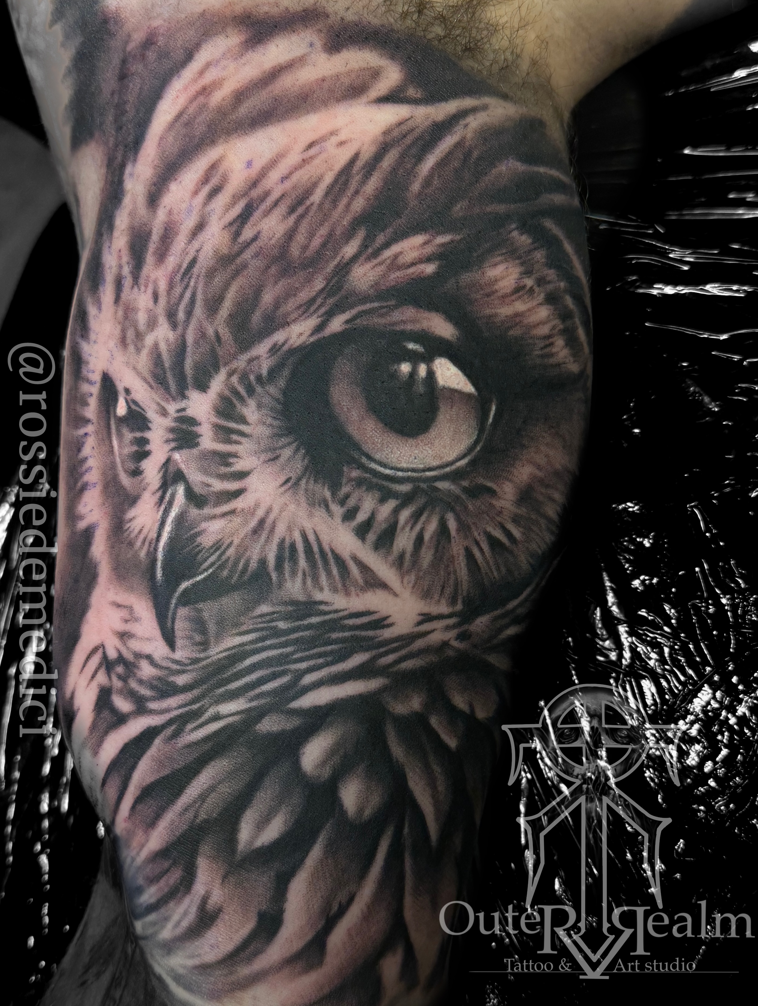 A detailed black and gray tattoo of a lion's face, focusing on the eye, with intricate shading and realistic features, on a person's upper arm.